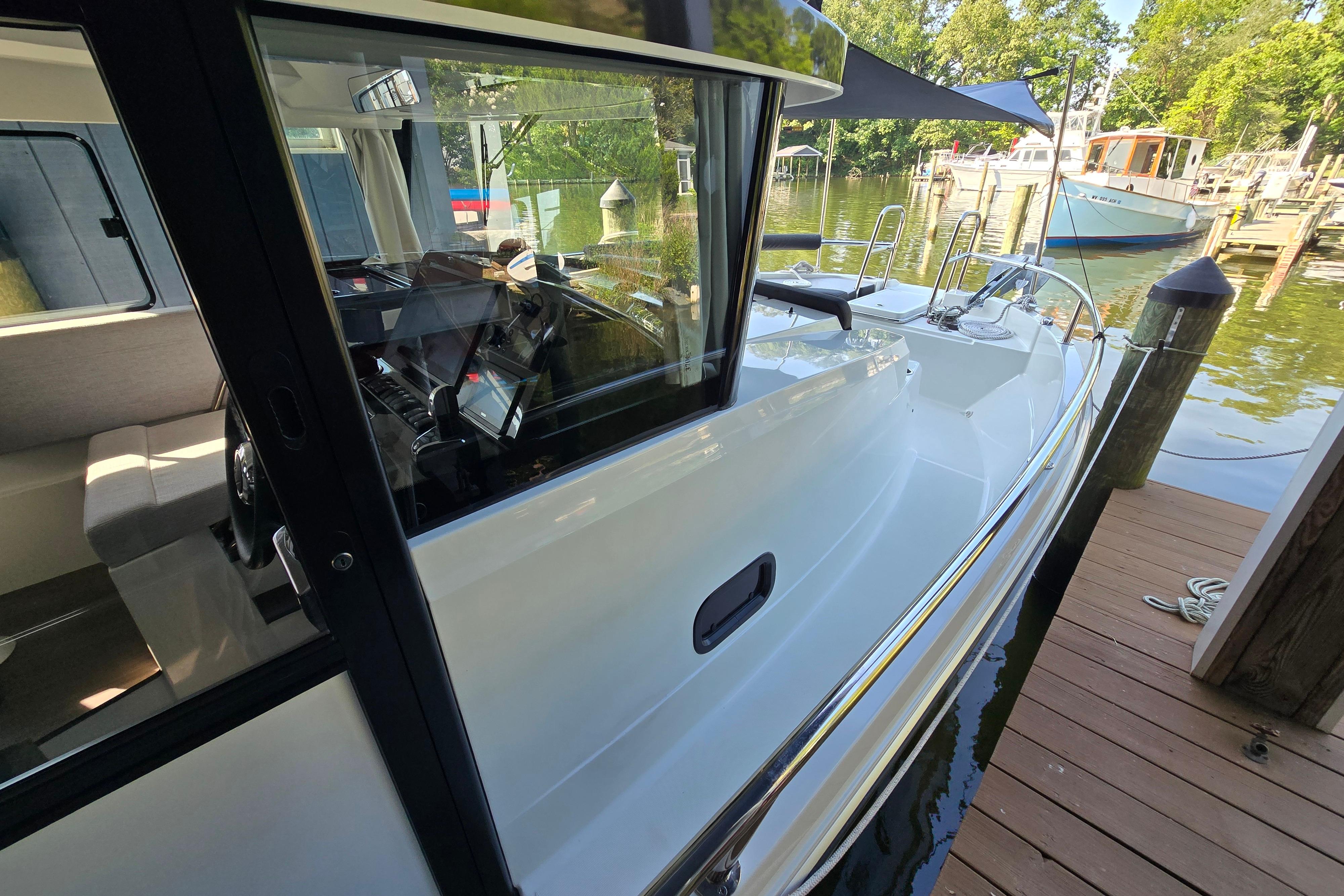 A modern boat docked at a wooden pier. It features sleek design and large windows.