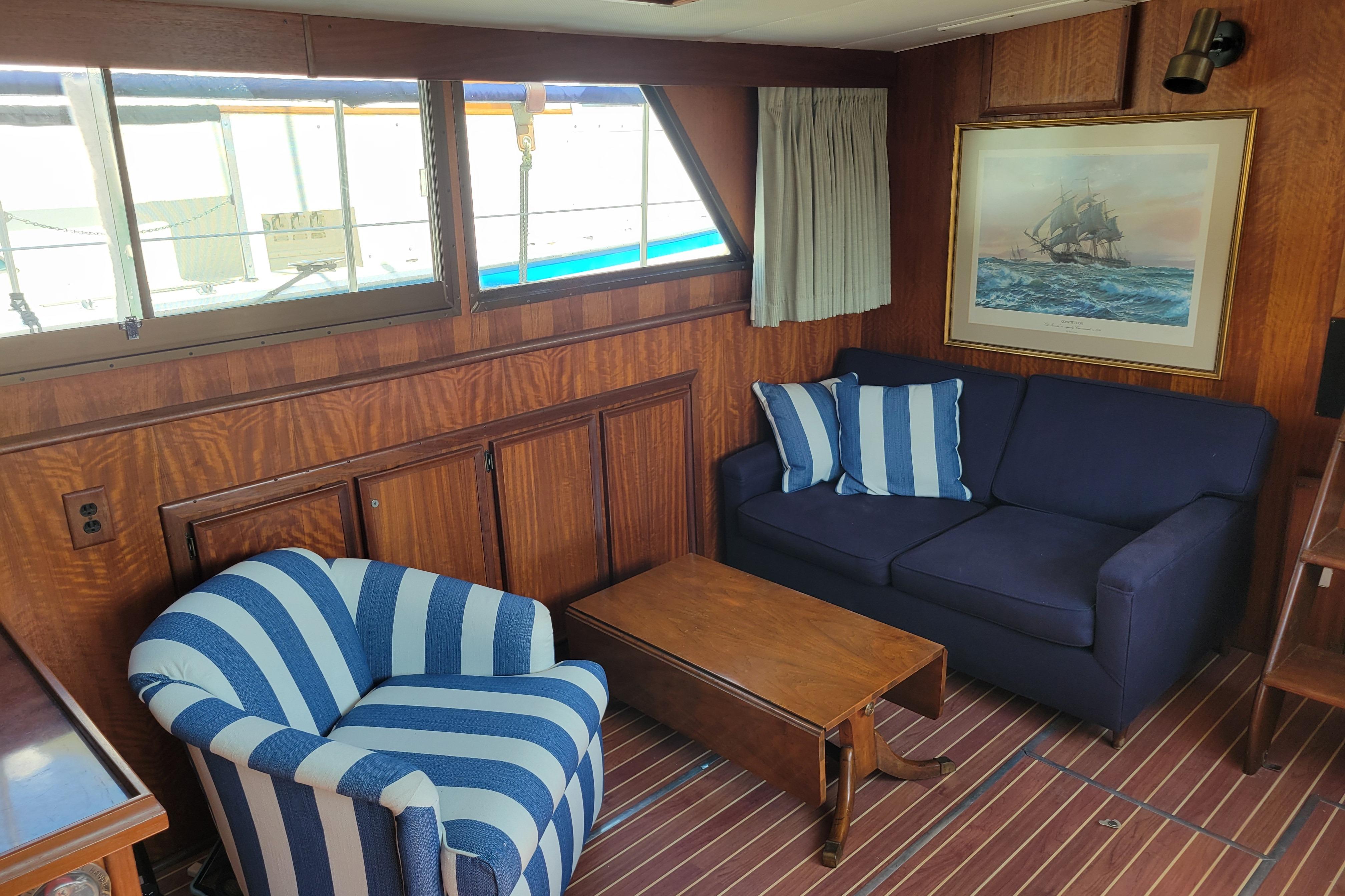 Interior of 1977 Hatteras 43 Double Cabin with striped chair, blue sofa, and nautical decor.