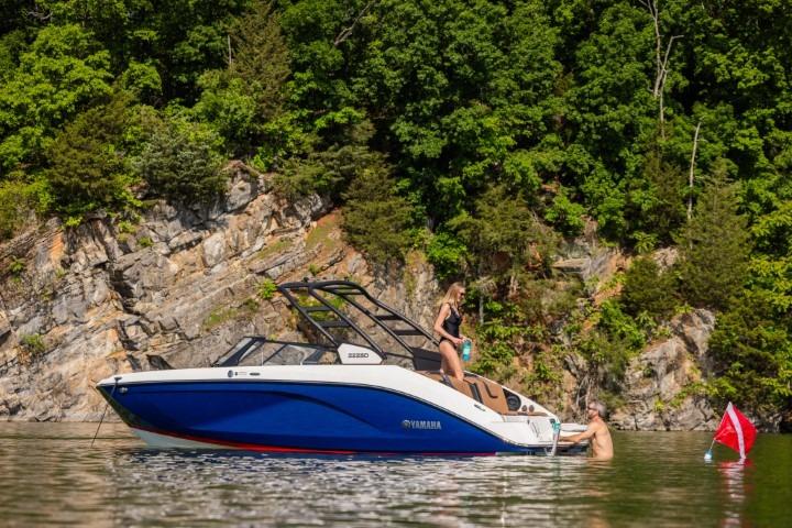 2026 Yamaha Boats 222SE on a scenic lake with lush greenery and rocky cliffs.