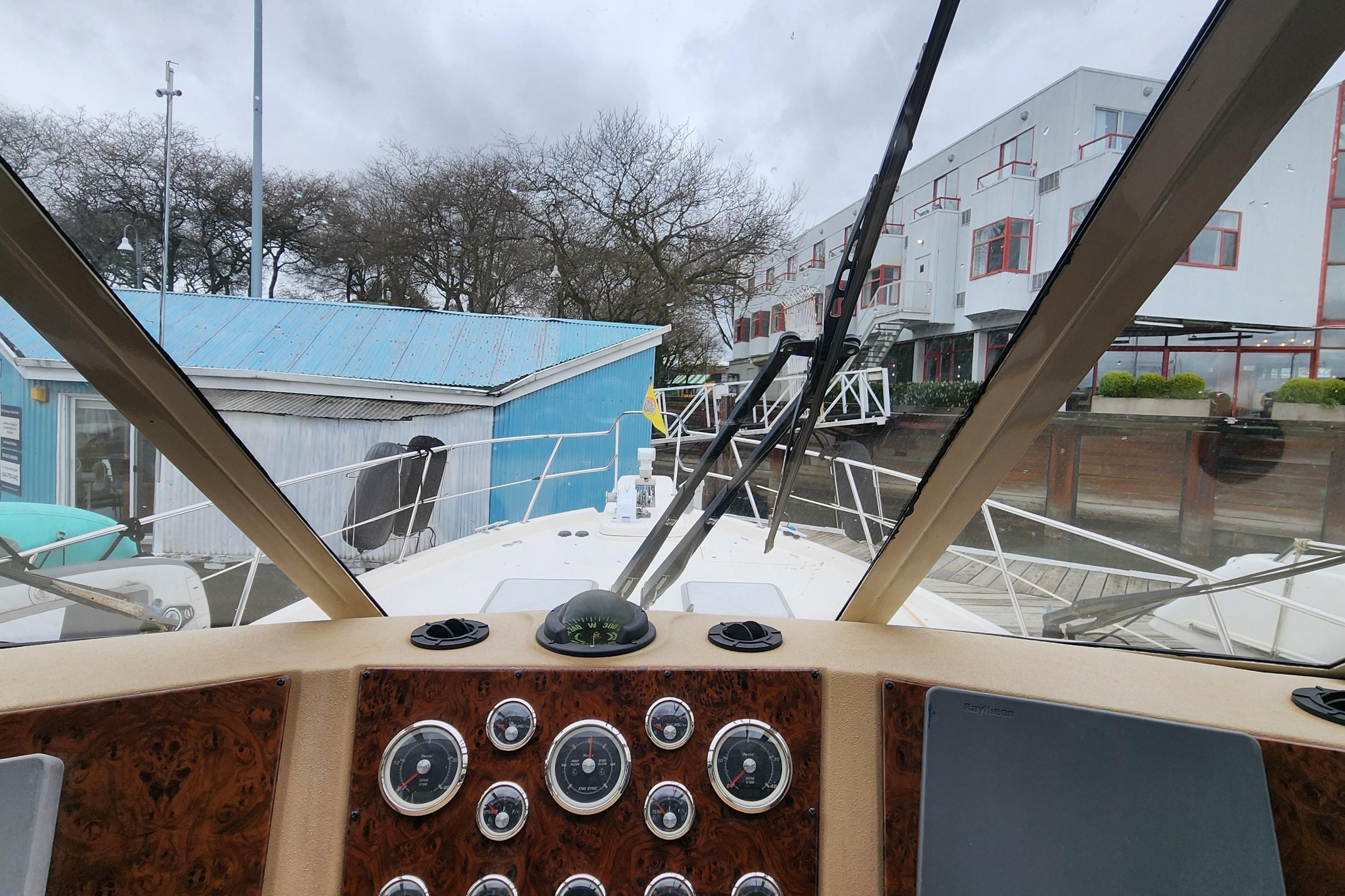 Pilothouse view from 2003 Meridian 490 yacht, showcasing dashboard and marina surroundings.