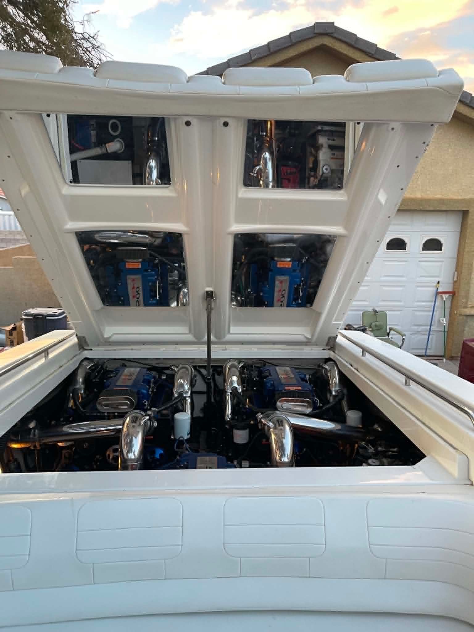 The engine compartment of a boat reveals two powerful engines with shiny components.