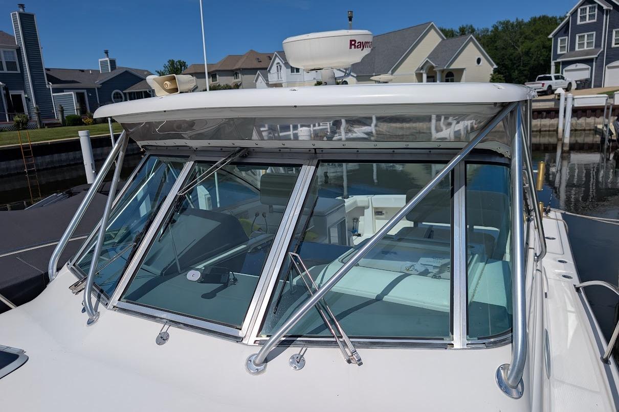 2000 Pursuit 3400 Express boat docked near waterfront homes, featuring a sleek windshield design.