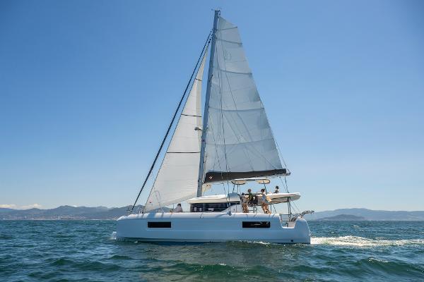 2025 Lagoon 43 sailing on open sea under clear blue sky.