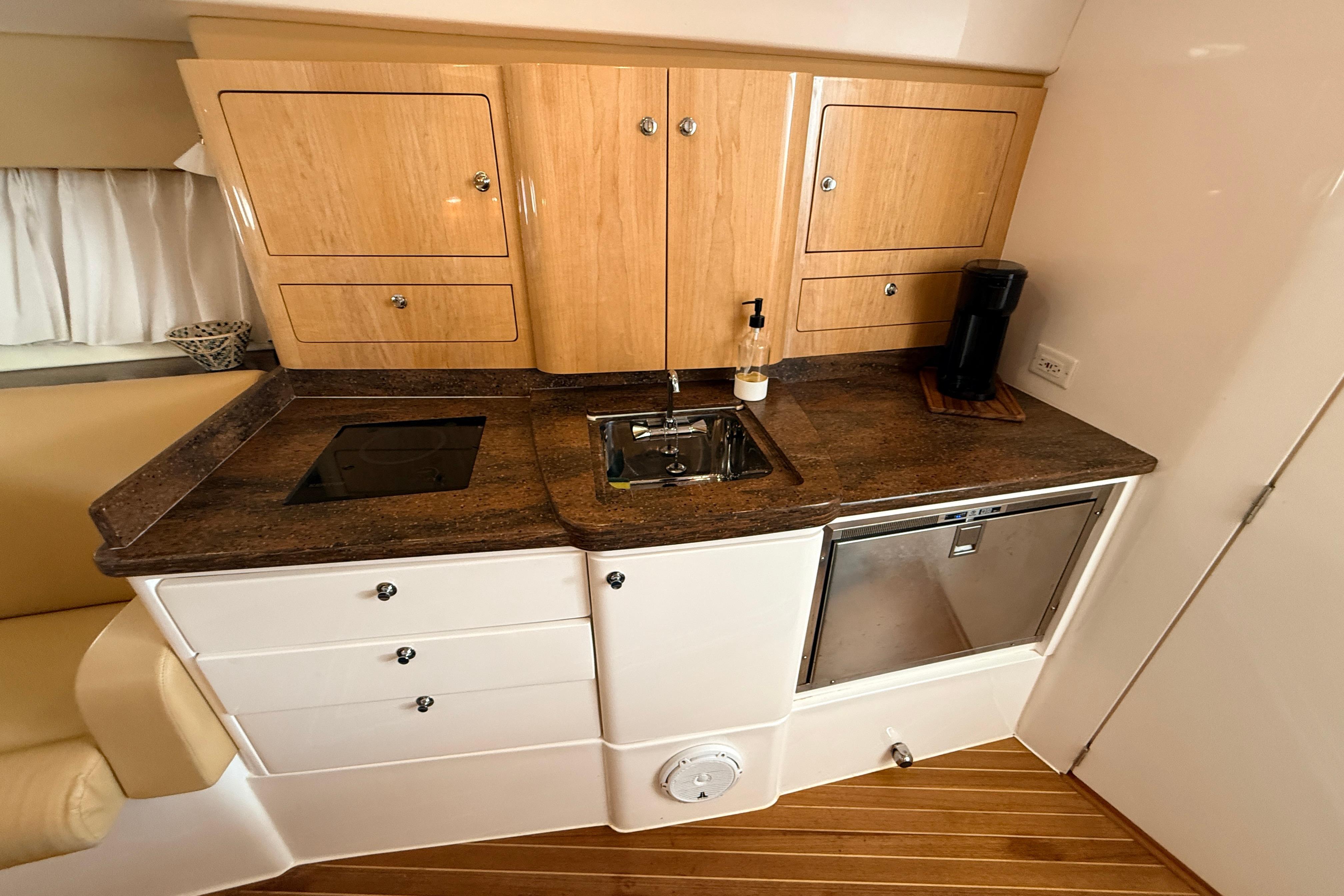 Compact kitchen area in a 2016 Intrepid 430 Sport Yacht with wooden cabinets and modern appliances.
