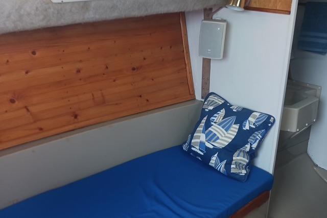 Interior of 1989 O'Day 272 sailboat with blue cushion and nautical-themed pillow.