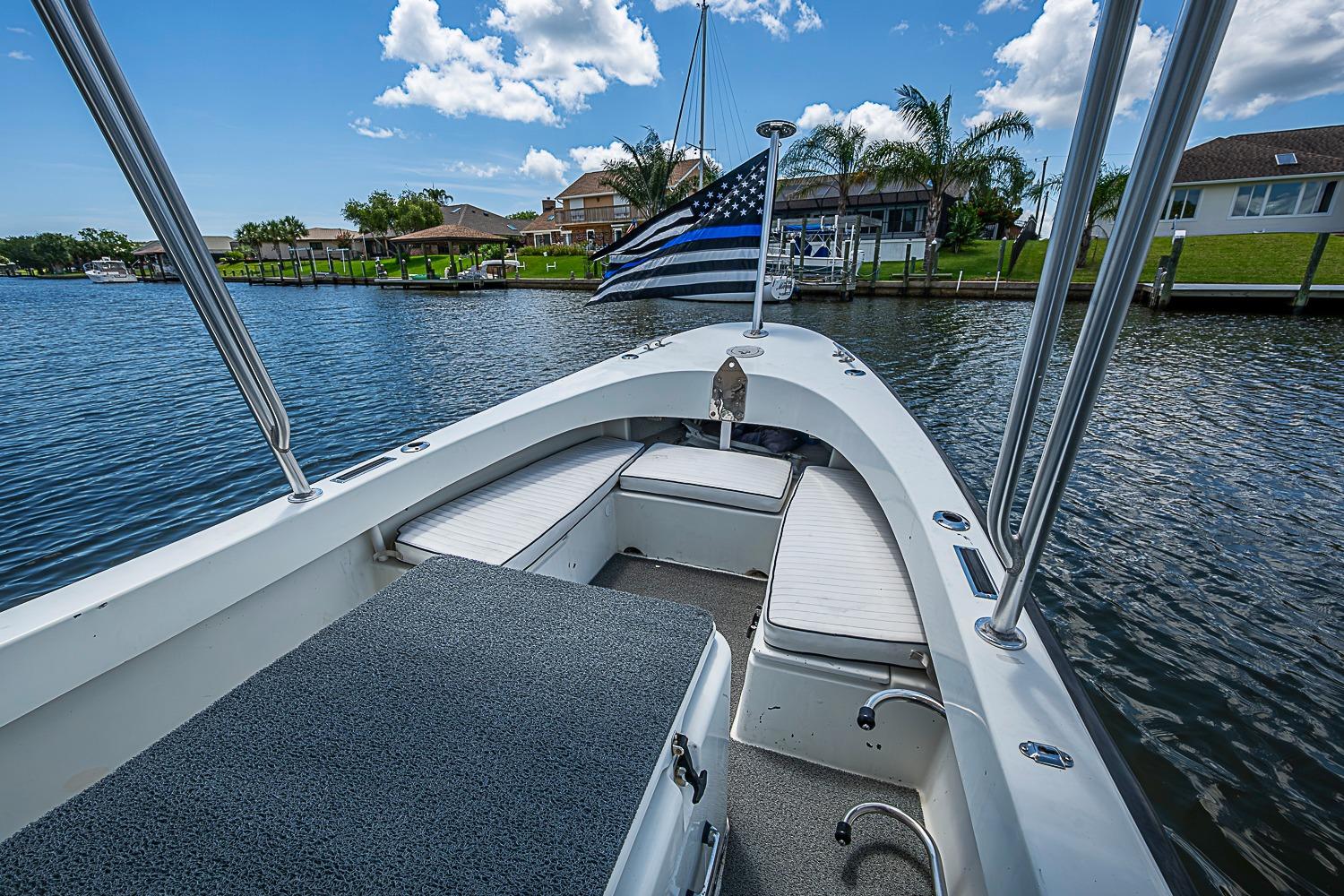 Custom 1969 boat with flag, docked in scenic waterfront neighborhood under blue sky.