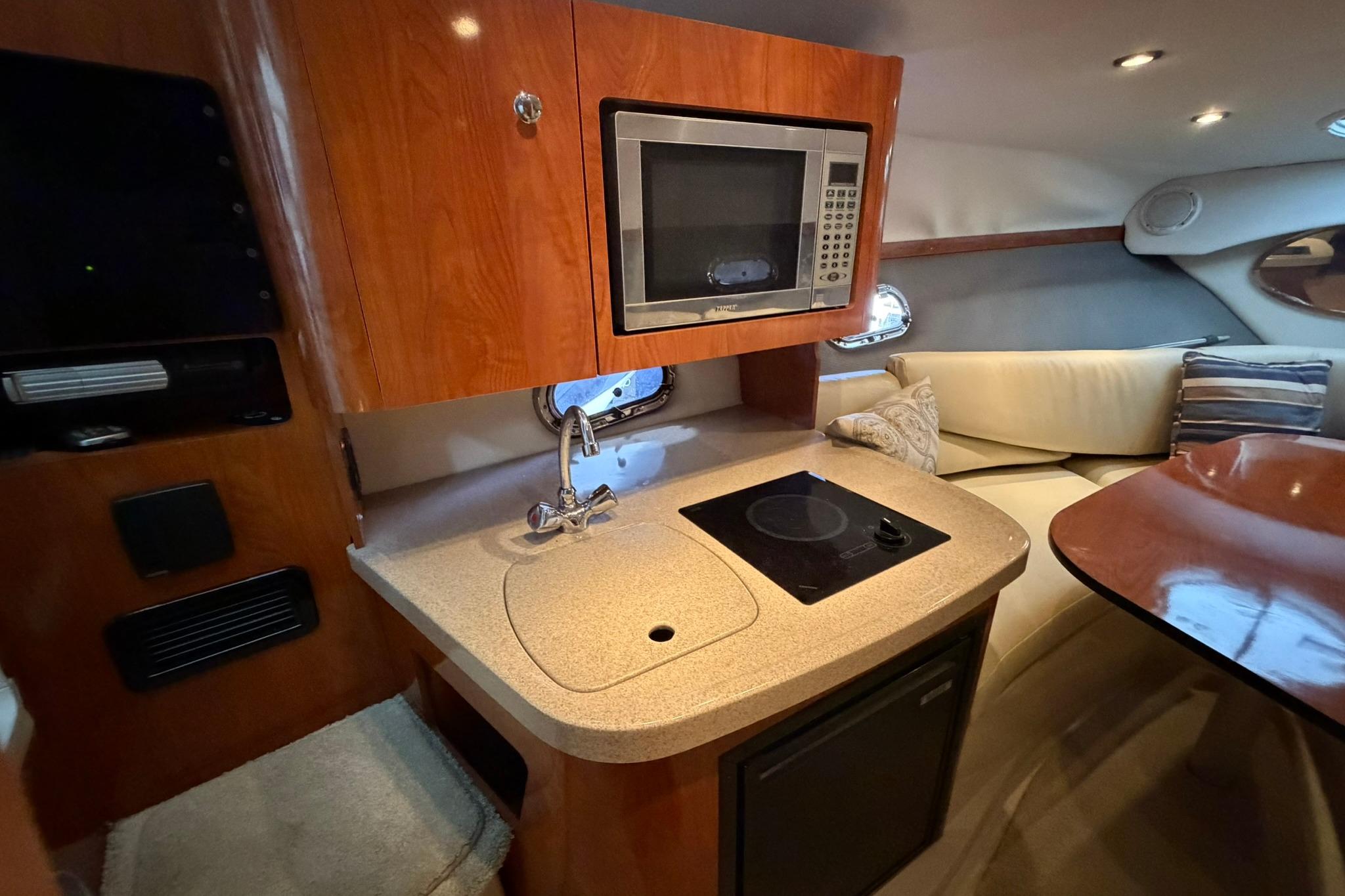Interior of 2008 Four Winns V248 boat featuring kitchenette with microwave and seating area.
