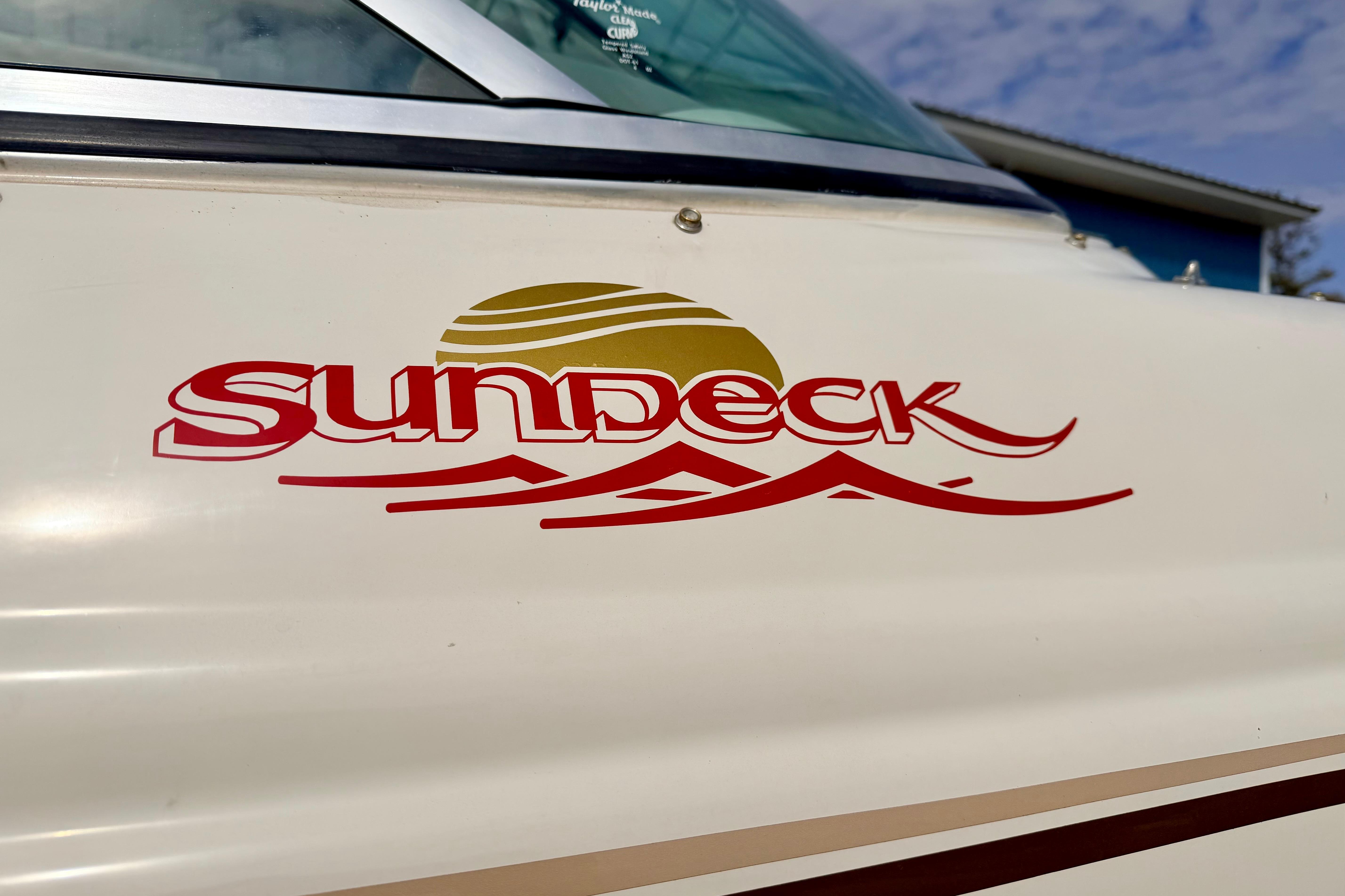 2003 Sea Ray 200 Sundeck logo on boat exterior, featuring sun and wave design.