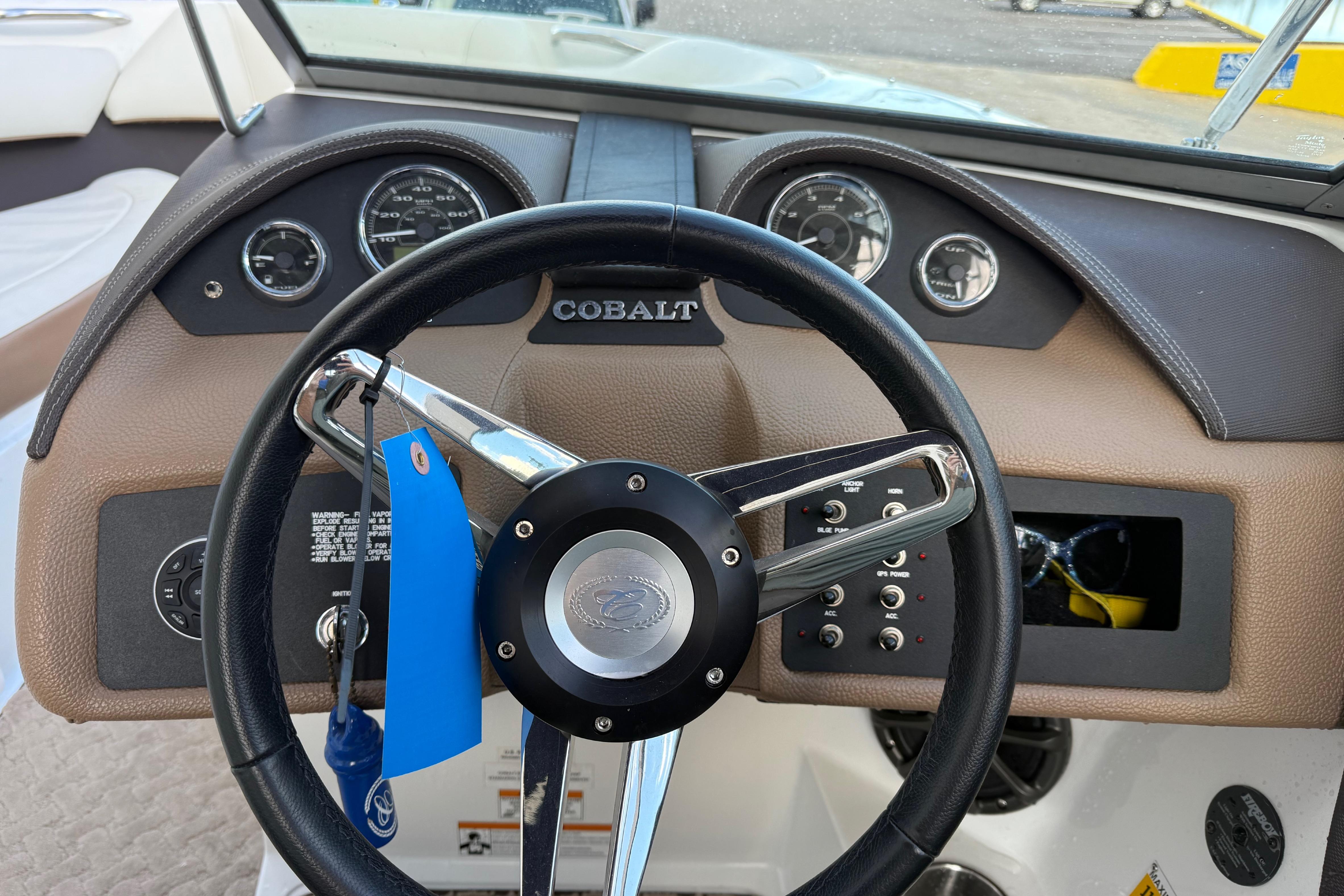 Steering wheel and dashboard of a 2015 Cobalt 200 boat, featuring gauges and controls.