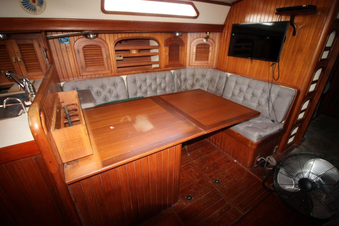 Cozy 1985 Passport 47 yacht interior with wooden dining area and cushioned seating.