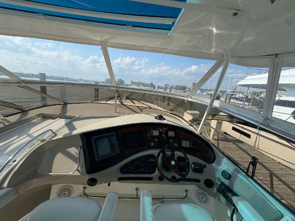 2003 Cruisers Yachts 540 Express helm with navigation controls, docked at marina under clear skies.