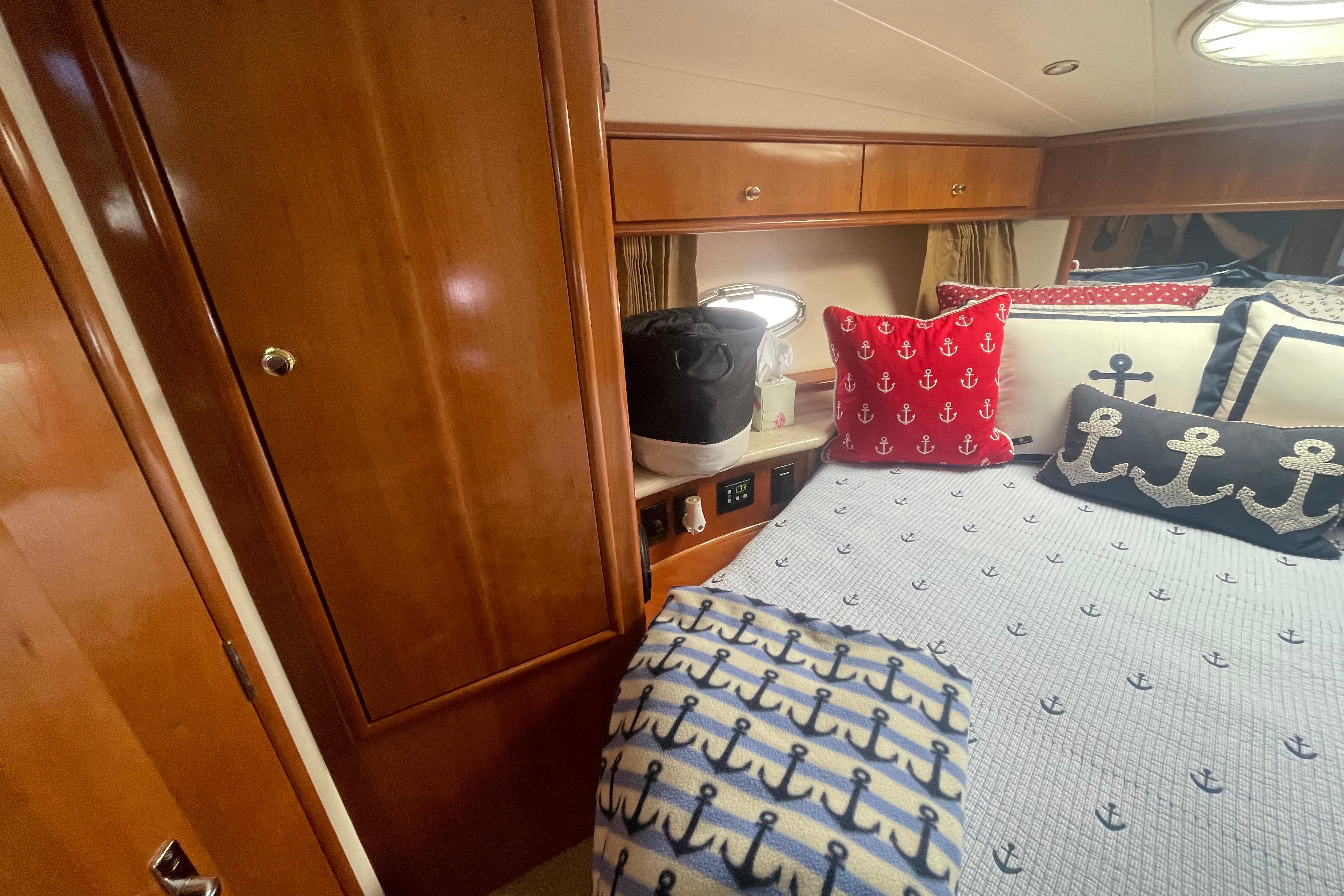 Luxurious 2002 Carver 410 Sport Sedan cabin with nautical-themed bedding and wooden cabinetry.