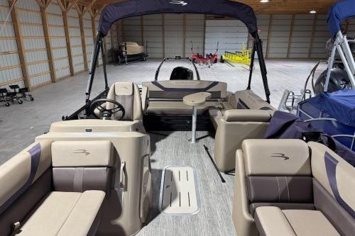2026 Bennington 22SXSB pontoon boat interior with seating and steering wheel in a spacious garage.