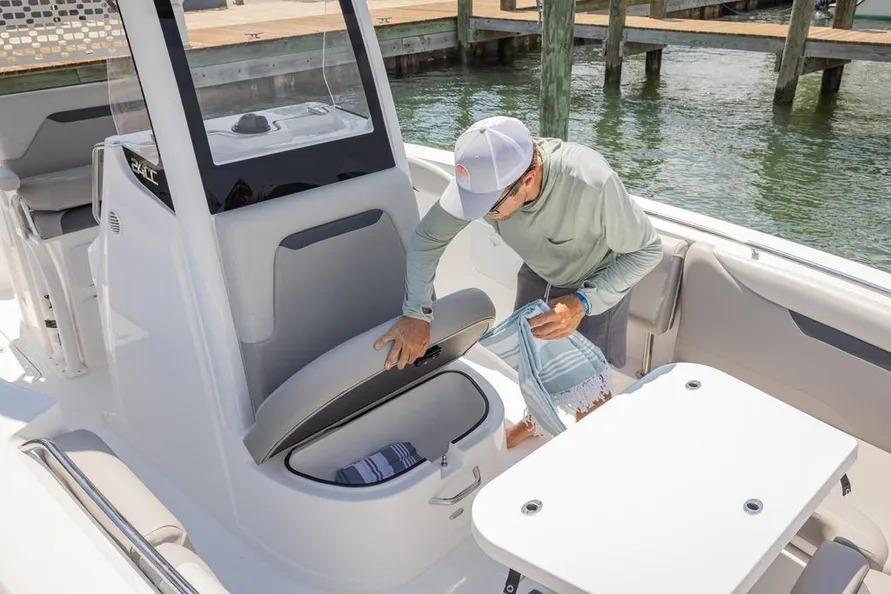 Man accessing storage on 2025 Hurricane Center Console 24 OB boat at dock.