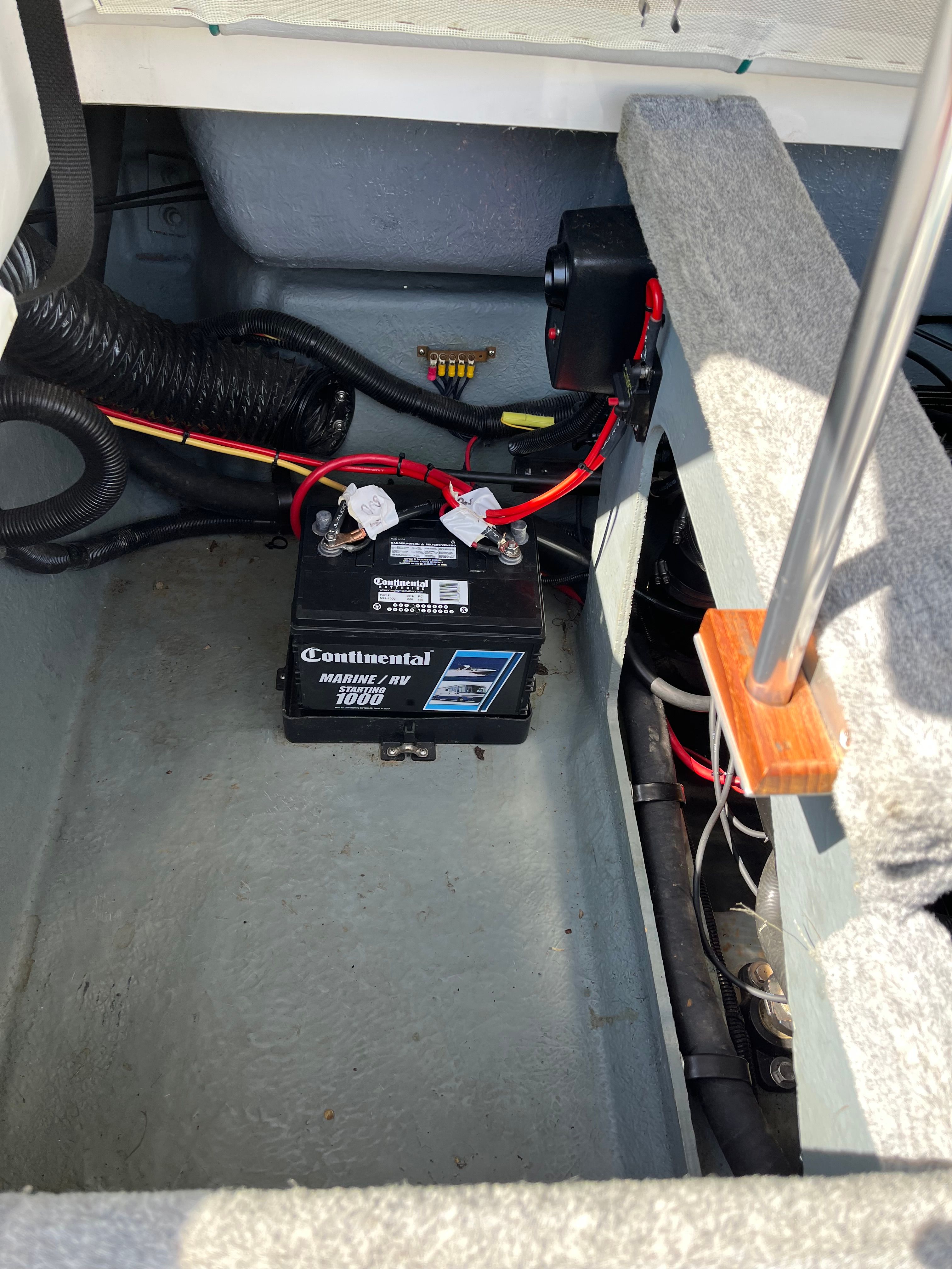 View of a boat's engine compartment with a battery and cables.