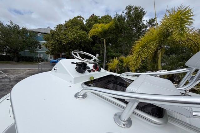 2025 Contender 26 Bay boat helm with steering wheel and controls, surrounded by tropical foliage.