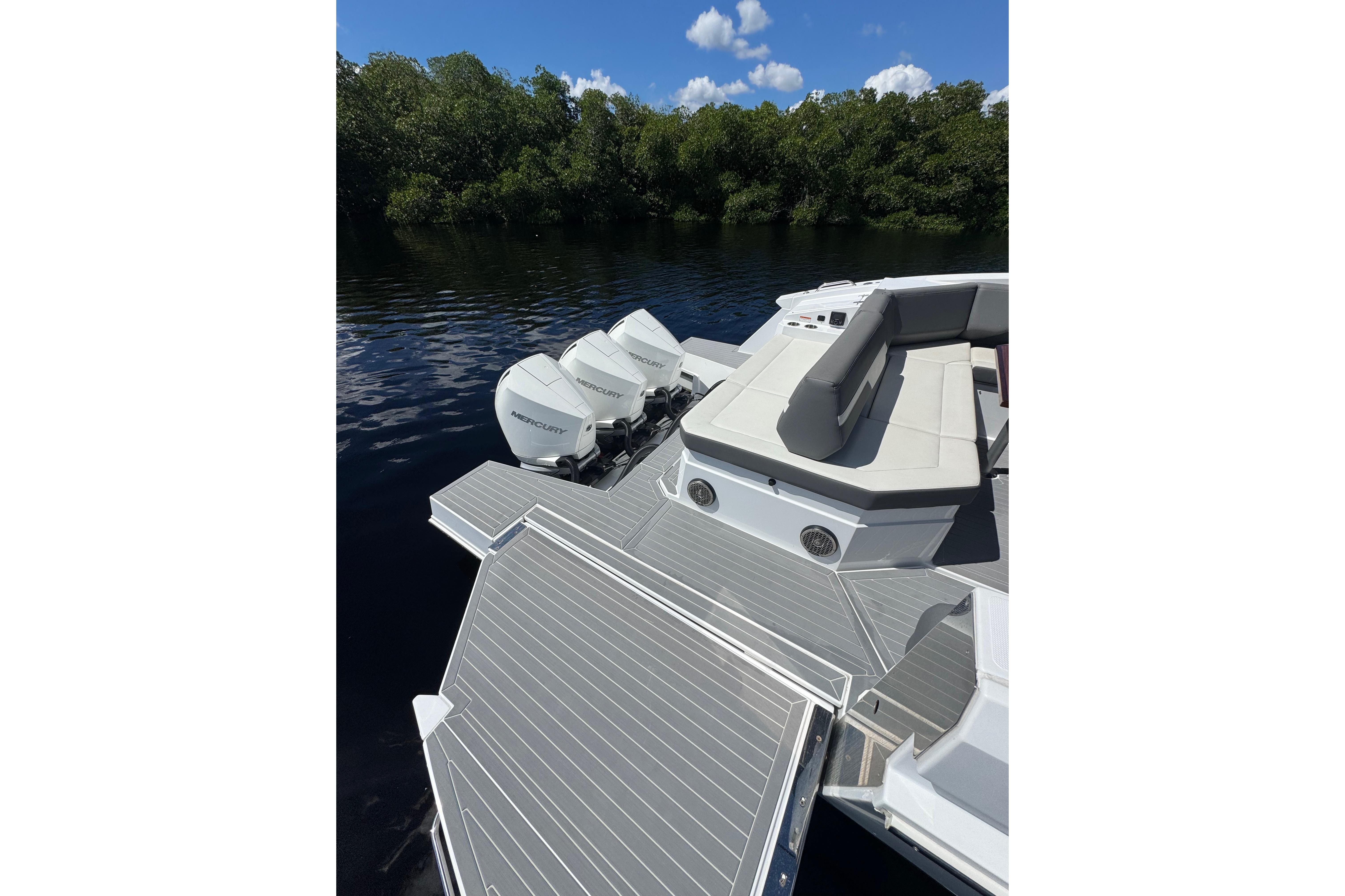 2022 Cruisers Yachts 38 GLS OB with triple Mercury outboards on a serene lake.