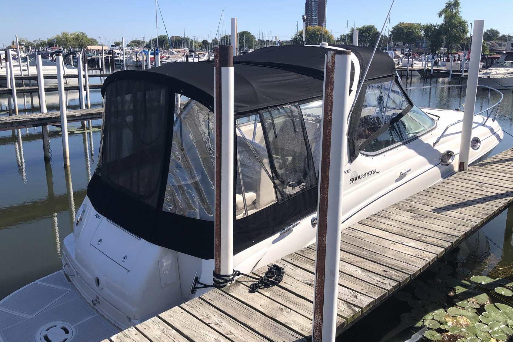 2005 Sea Ray 280 Sundancer docked at marina with black canopy.