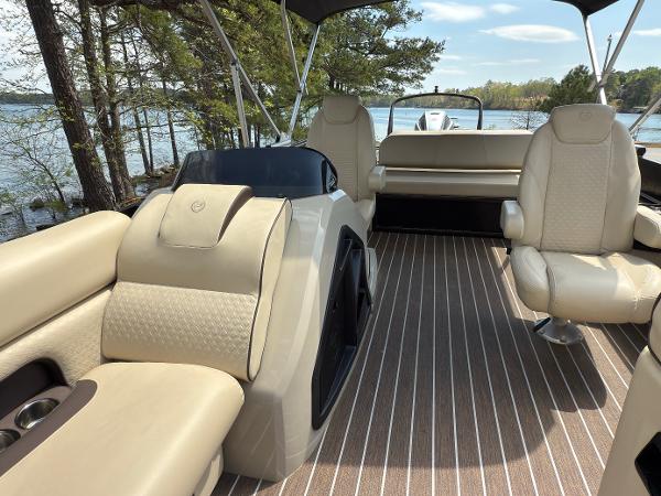 2022 Premier 250 Solaris boat interior with beige seating and striped flooring, near a scenic lake.