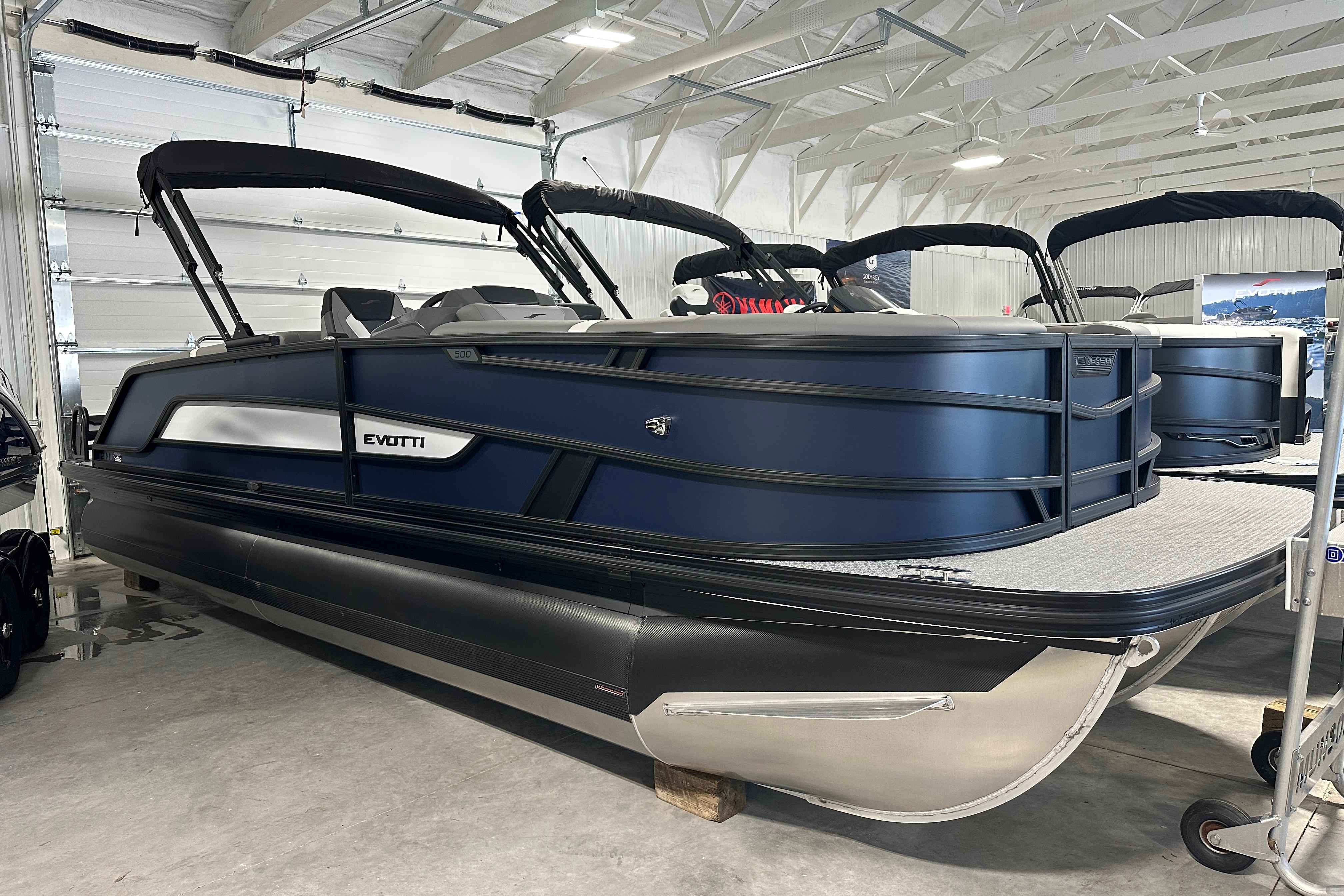 2026 Evotti 523QL pontoon boat in showroom, sleek design, black and blue color scheme.