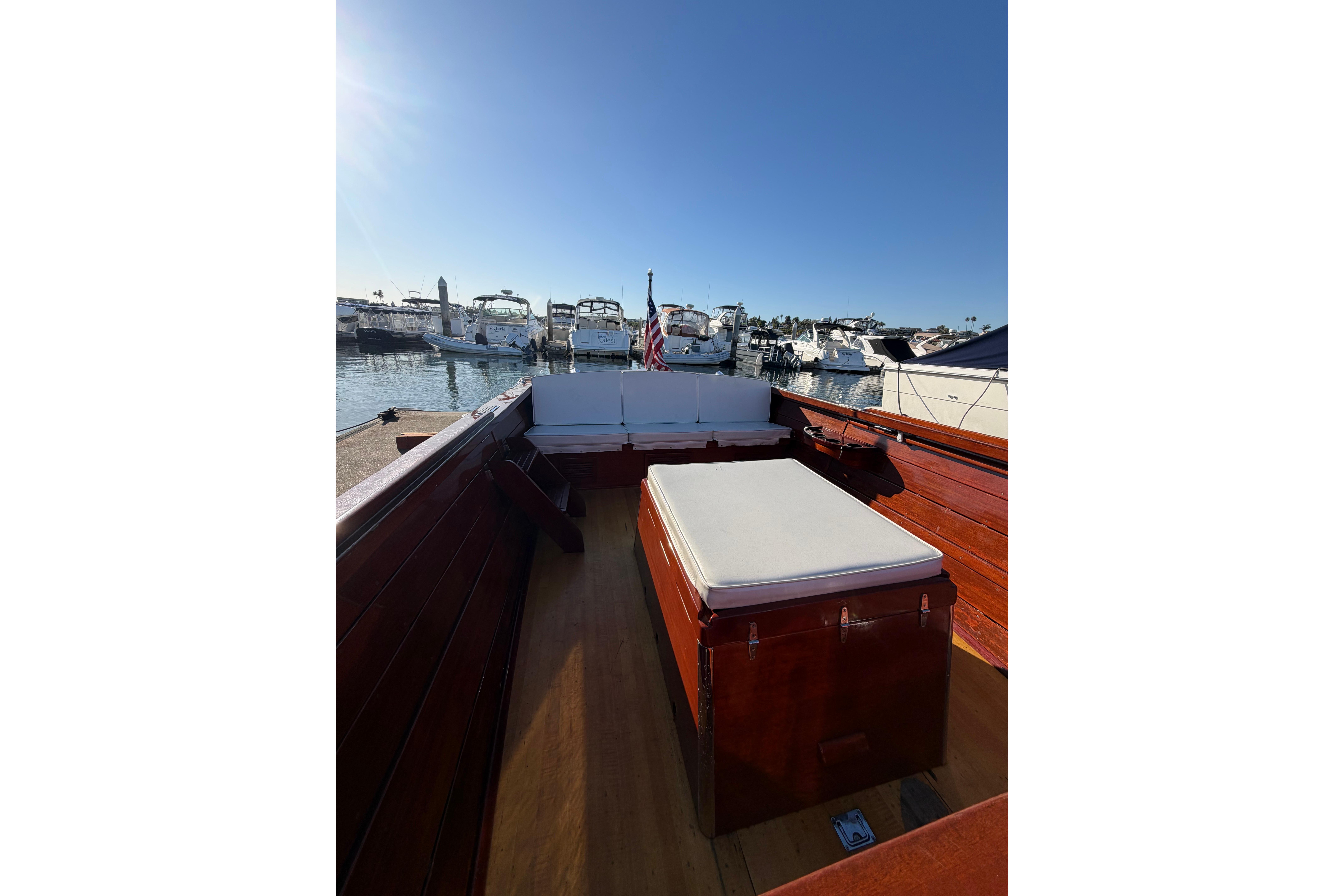 1964 Lyman 25 Sleeper boat interior with wooden finish, docked at a marina under clear blue sky.