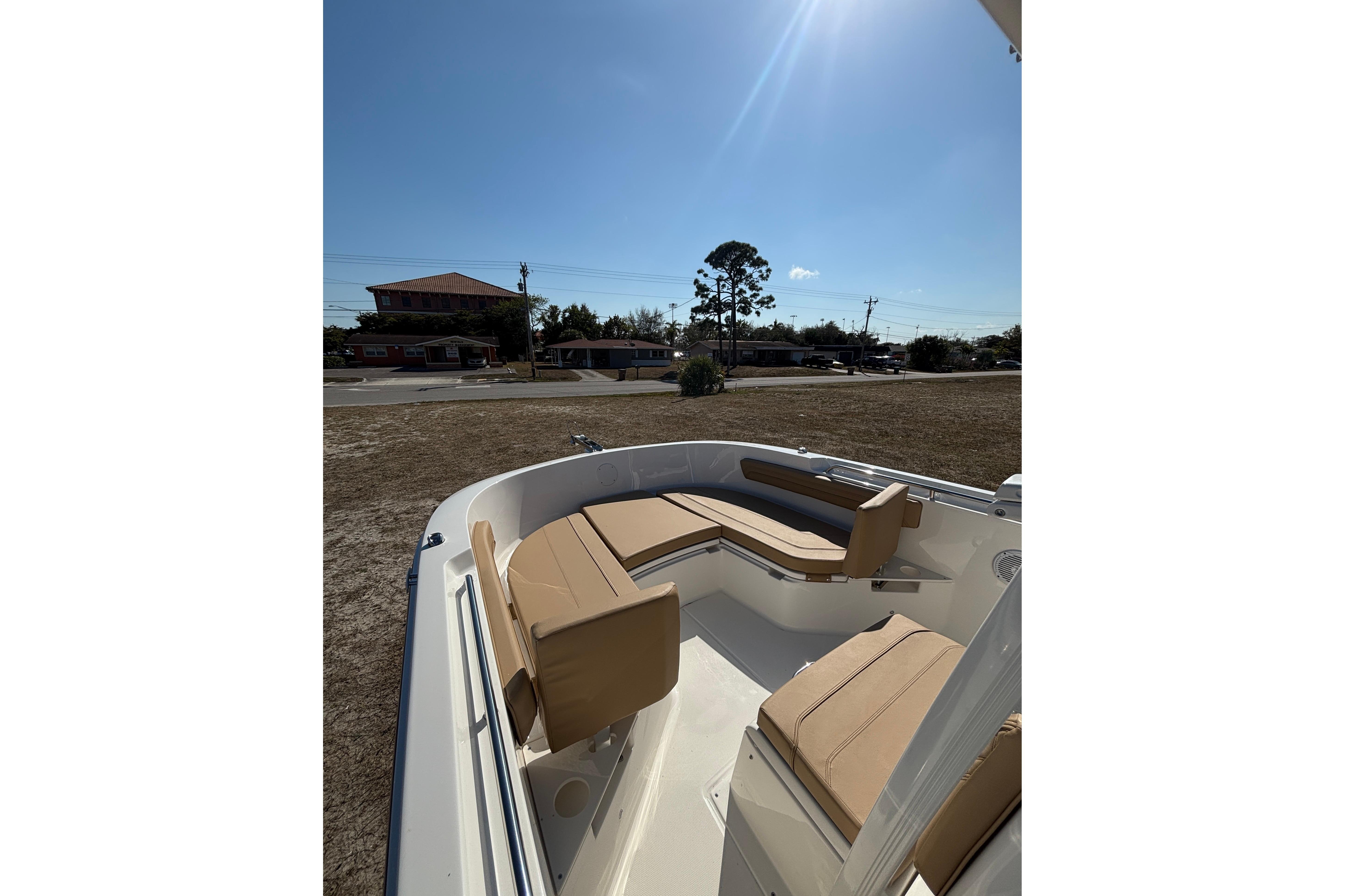 2026 Bayliner Trophy T22CC boat with tan seating, parked outdoors under clear sky.