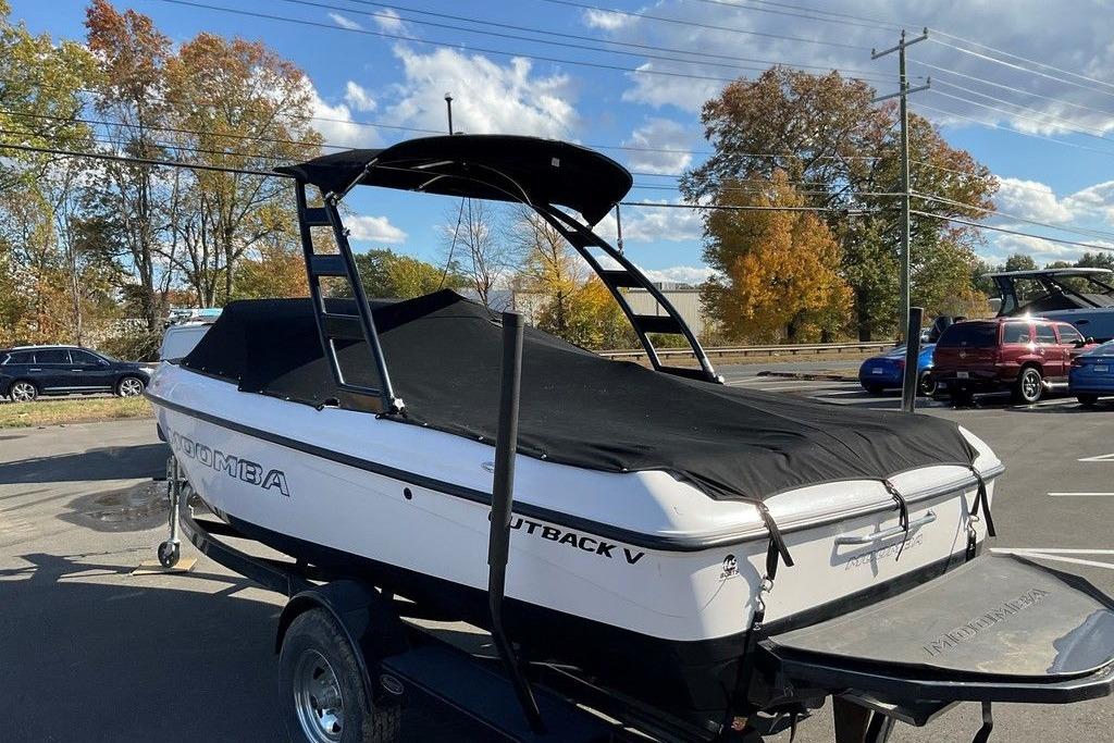 2015 Moomba Outback V boat with cover on trailer, parked outdoors.