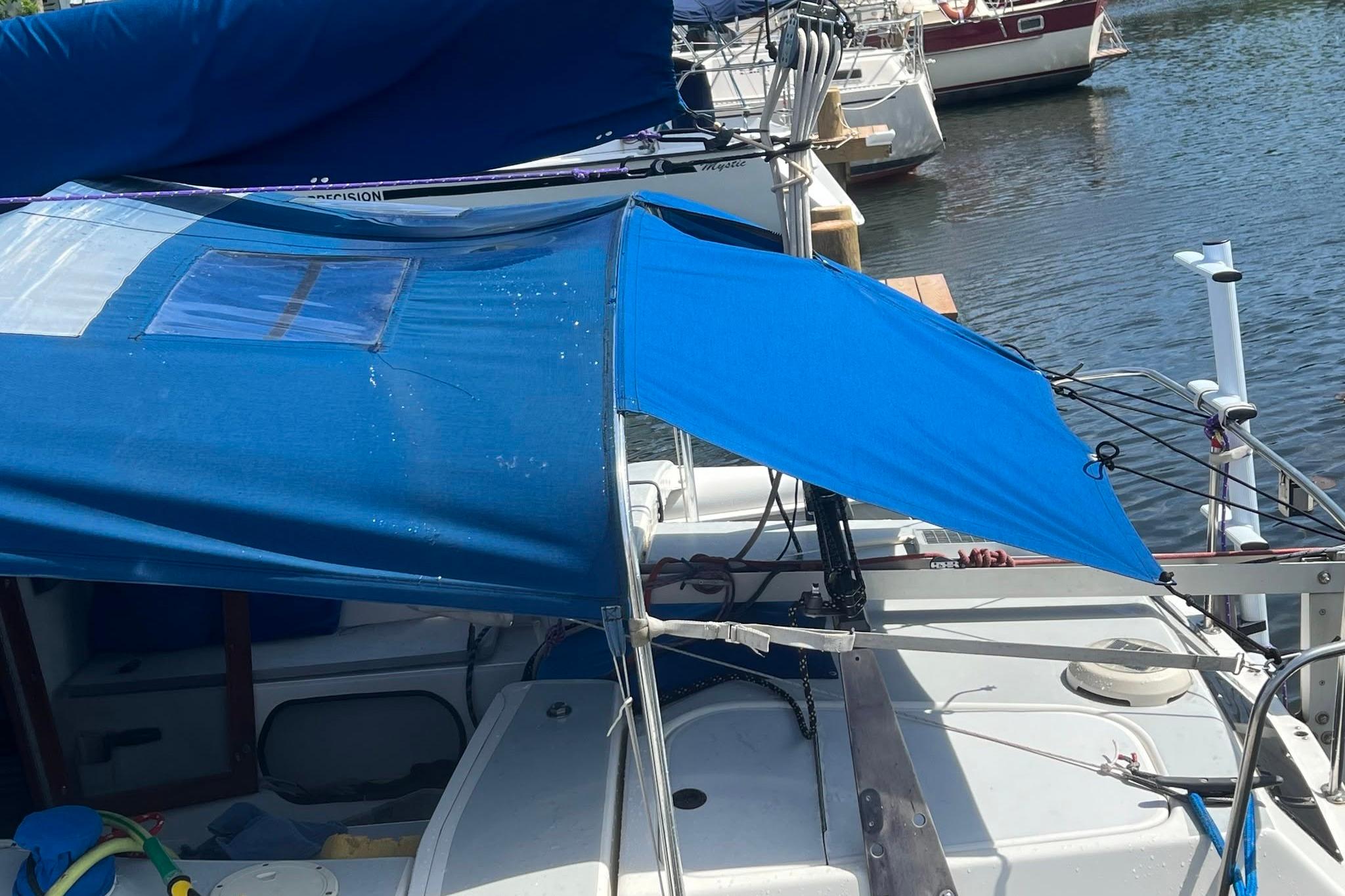 1993 Corsair F-27 sailboat with blue canopy docked at marina.