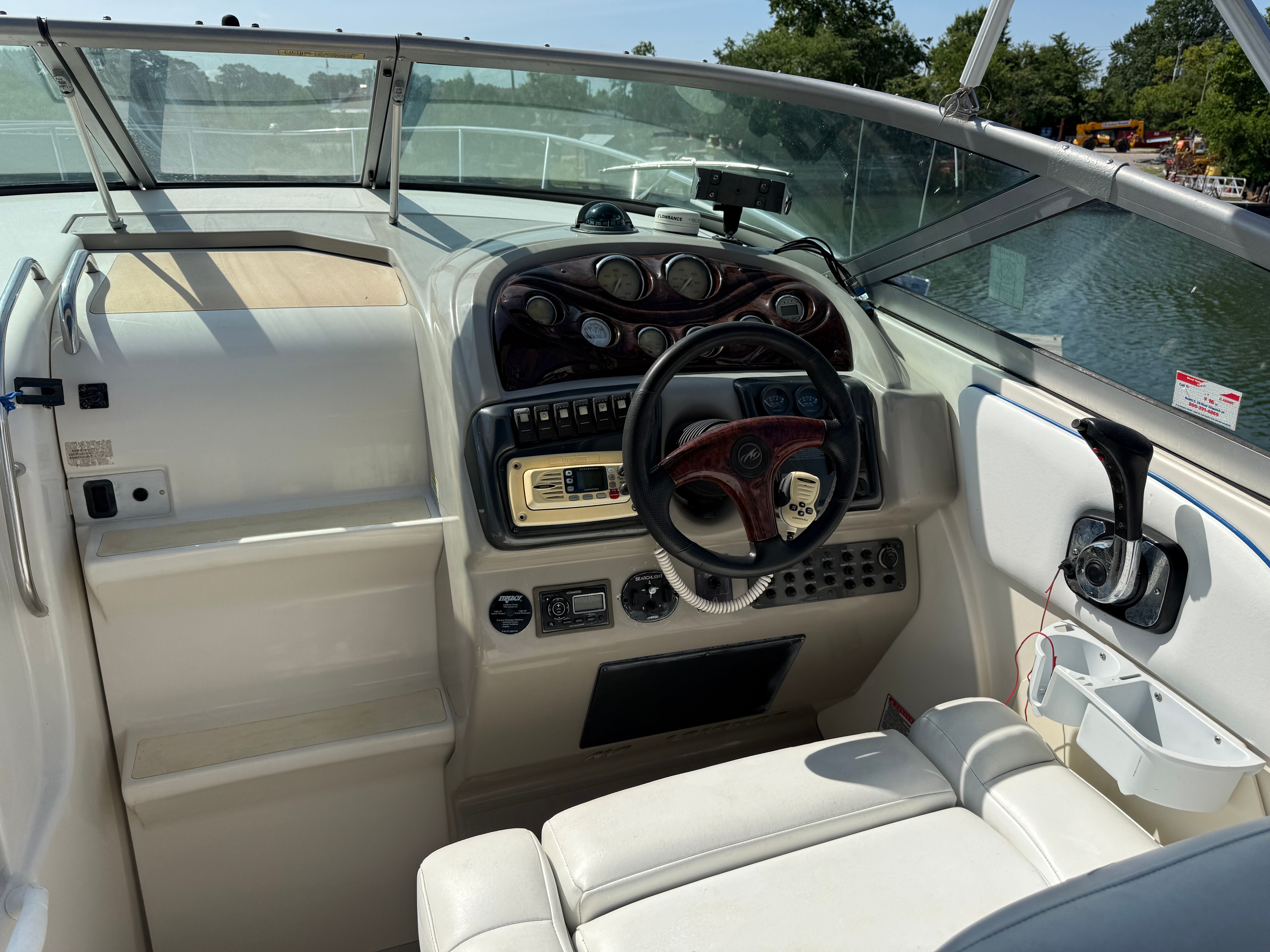 The cockpit of a 2006 Monterey 270 Cruiser with a sleek dashboard and wooden steering wheel.