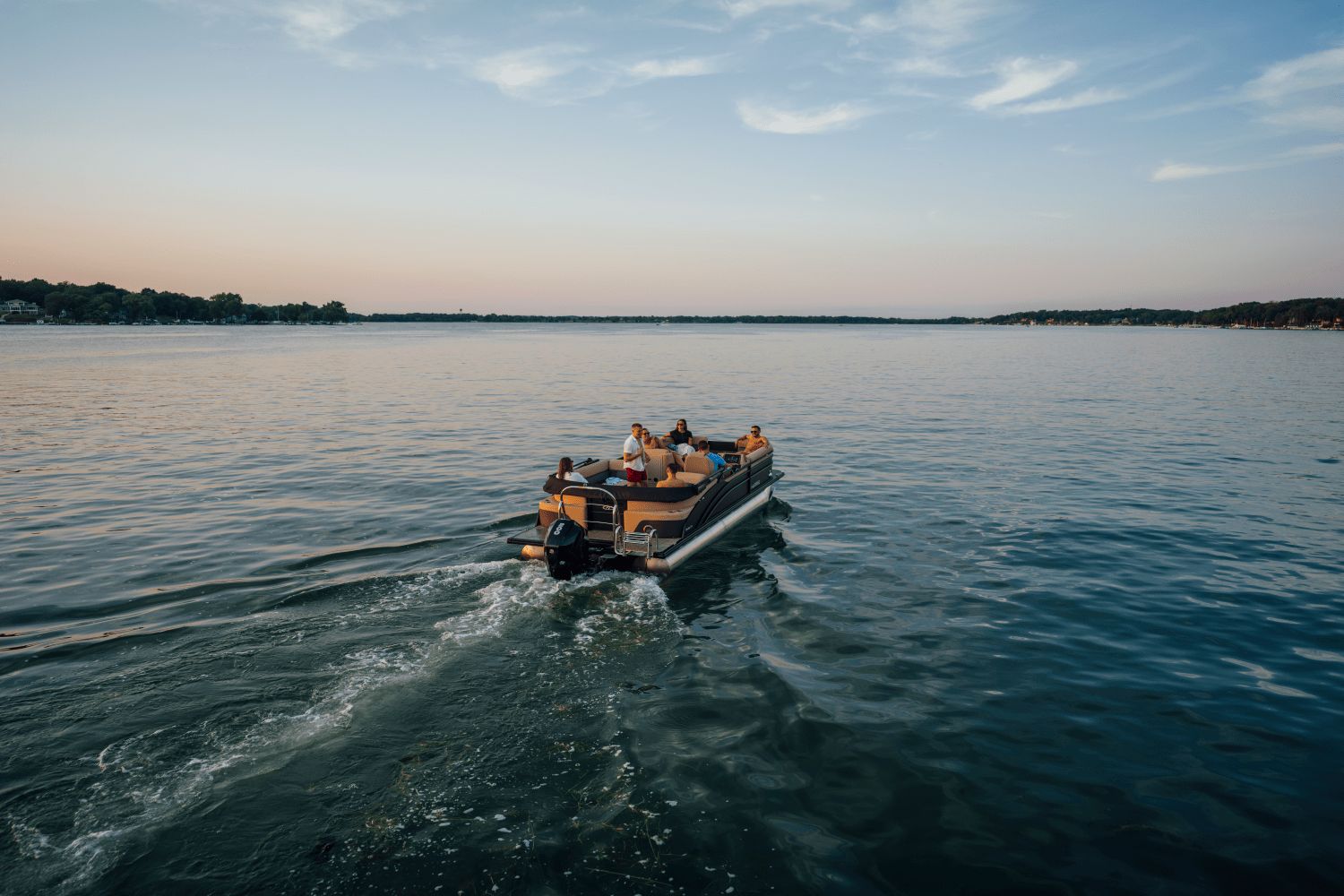 2026 Harris Cruiser 230 on a calm lake at sunset.