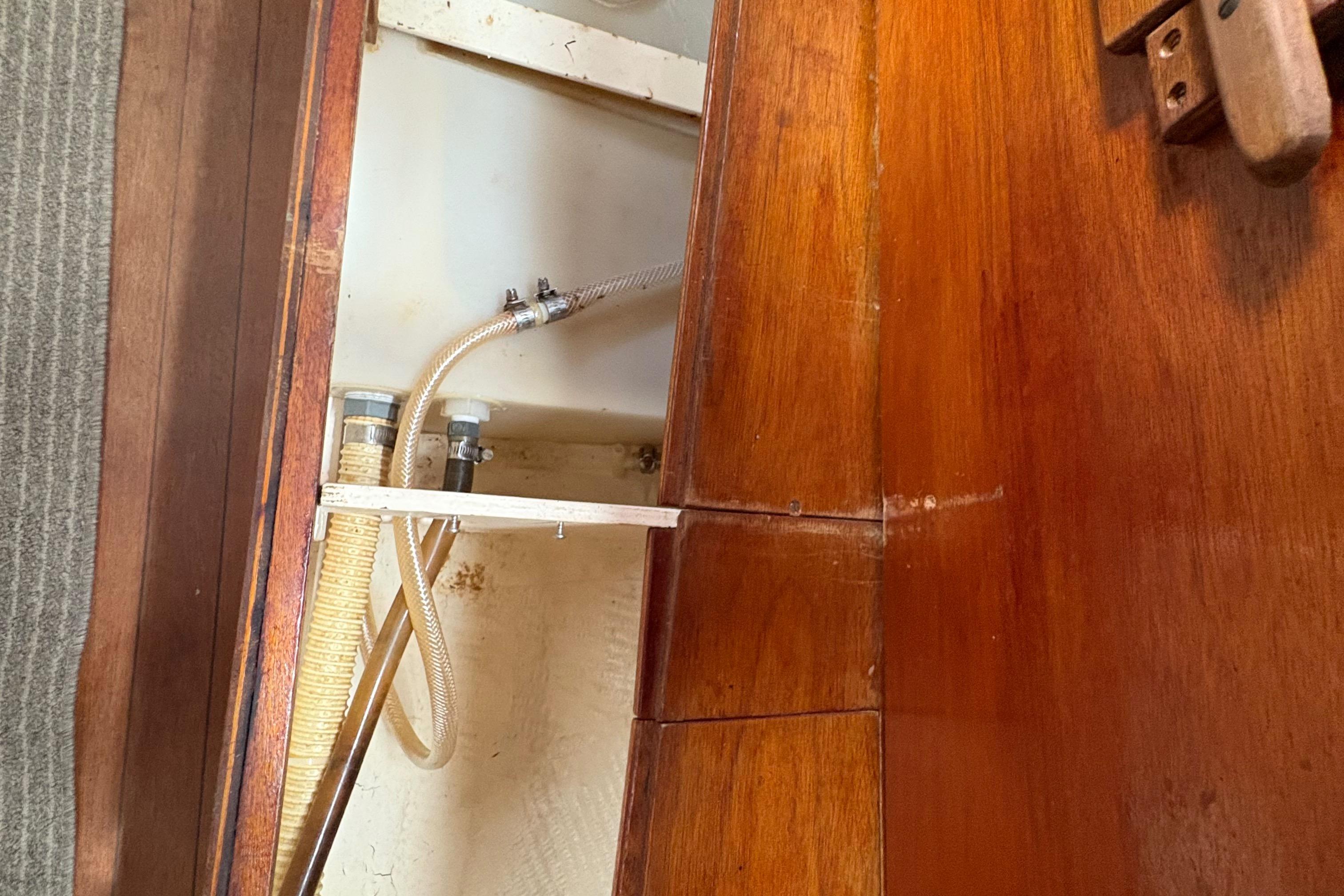 Interior view of 1981 Sabre 31 sailboat showing wooden cabinetry and plumbing hoses.