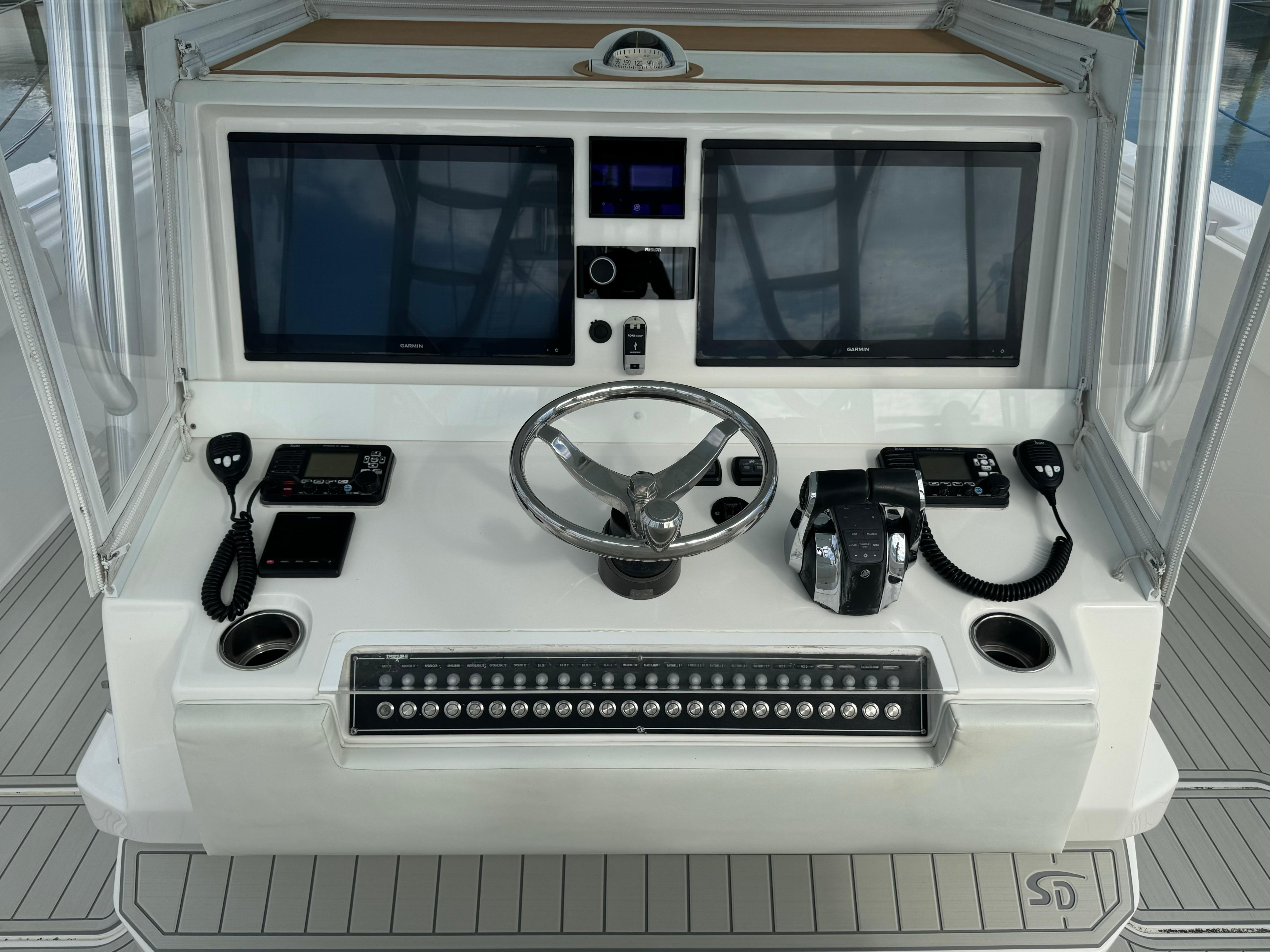 Control panel of a 2020 Invincible 40 Catamaran with dual screens and steering wheel.