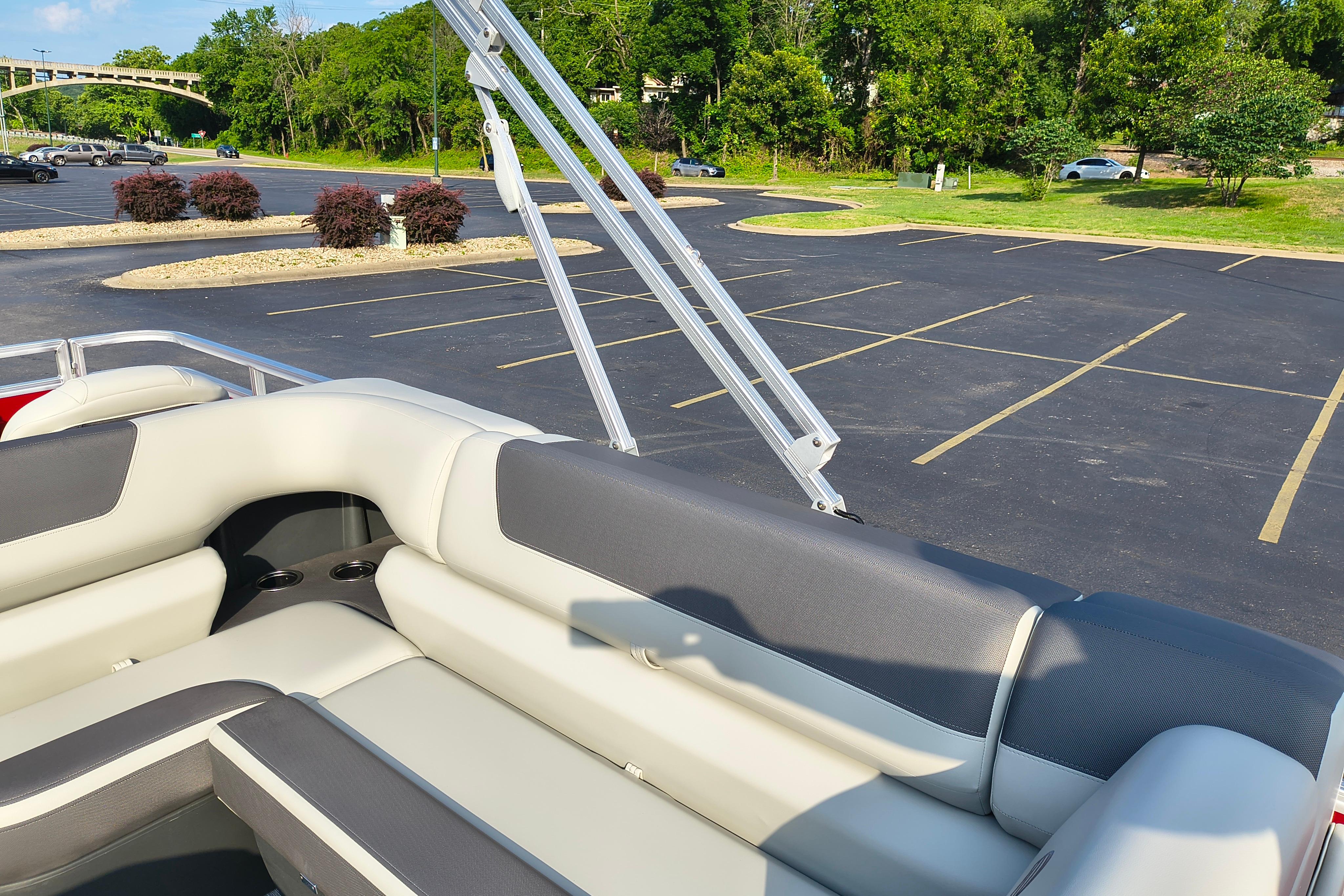 2026 Sun Tracker Fishin' Barge 22 DLX interior with plush seating in a parking lot setting.