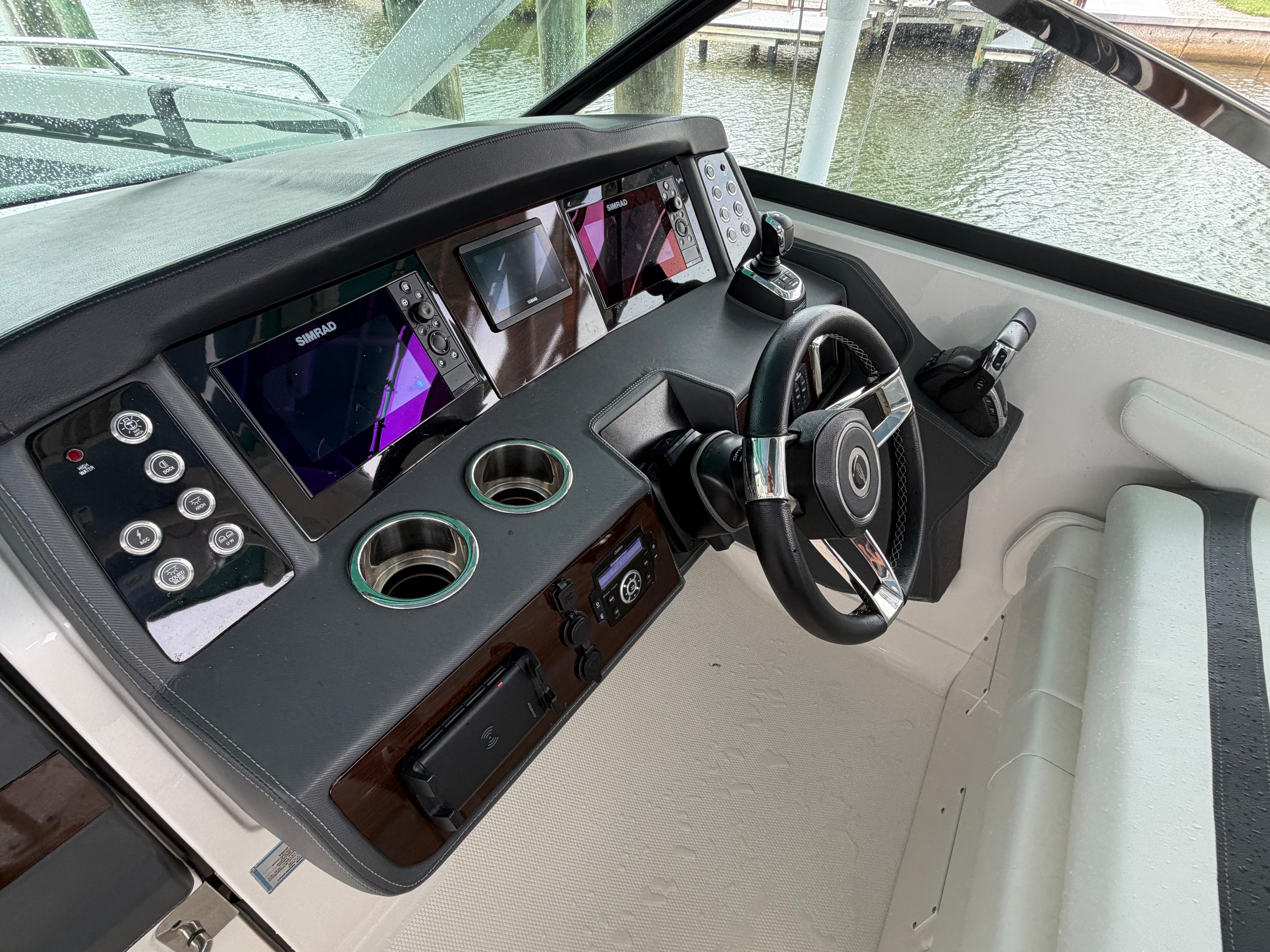 The cockpit of a modern boat with multiple screens and a steering wheel.