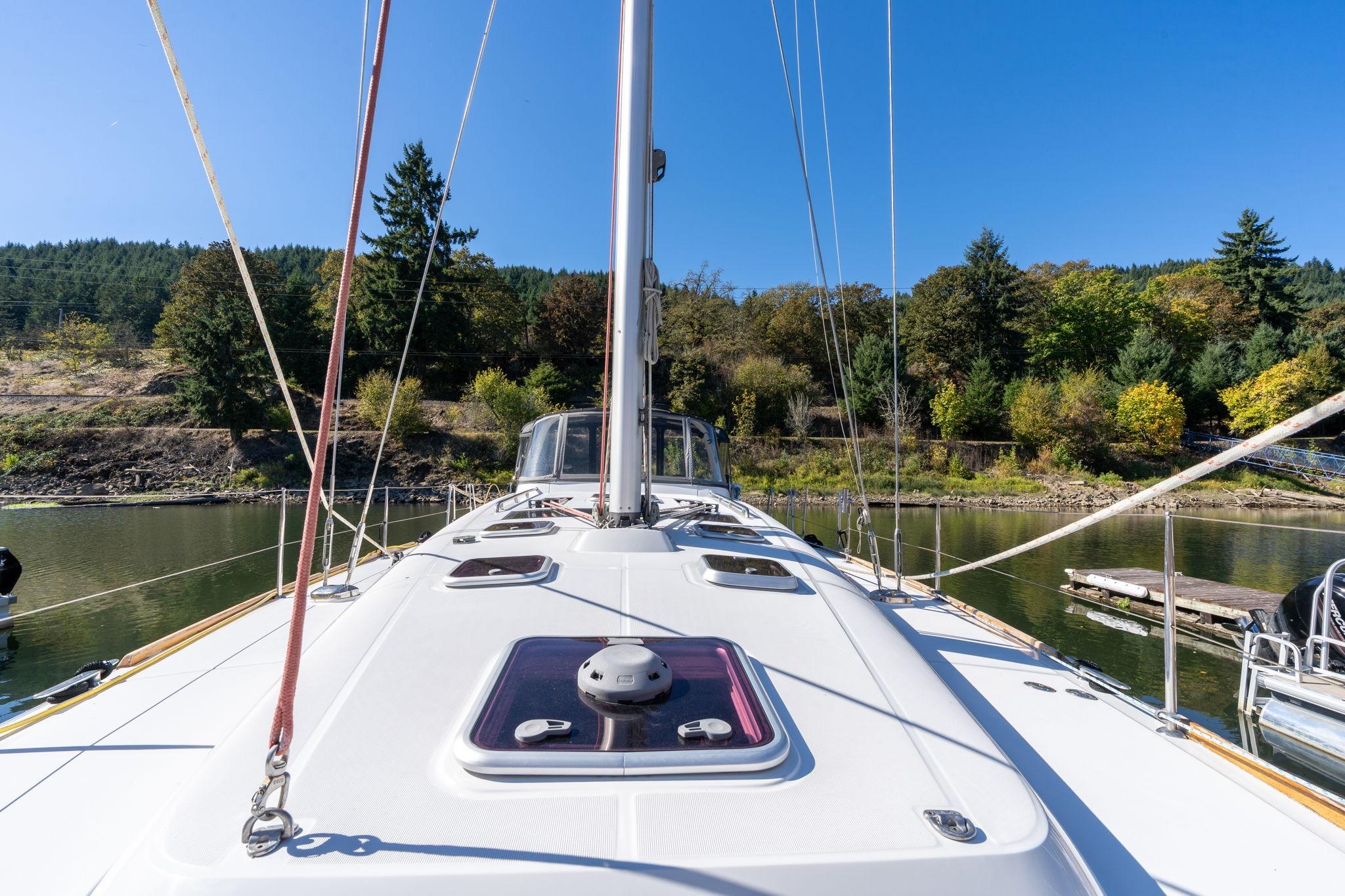 2013 Beneteau Oceanis 50 sailboat on calm water, surrounded by lush greenery.