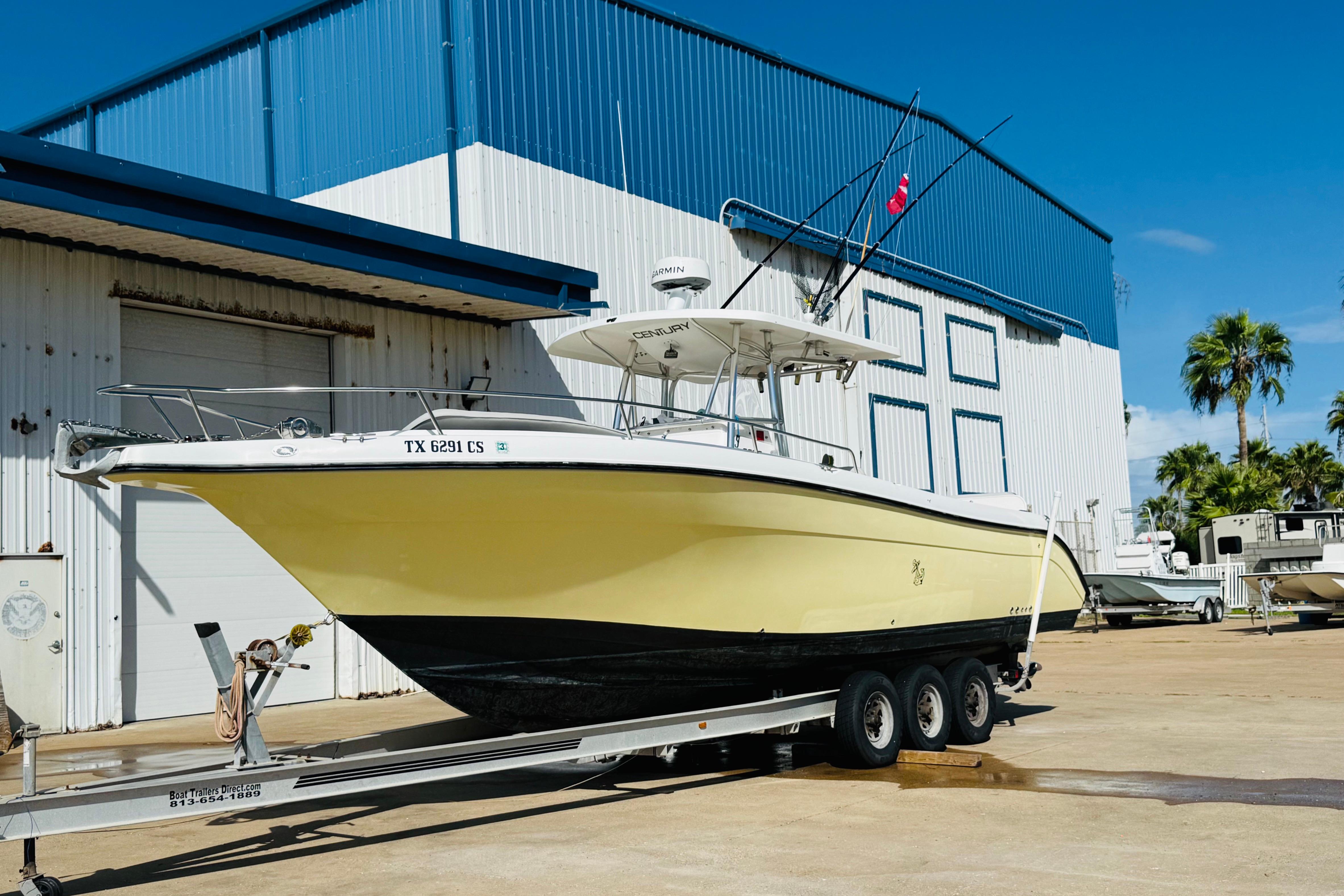 2005 Century 3200 Center Console boat on trailer outside a blue and white building.