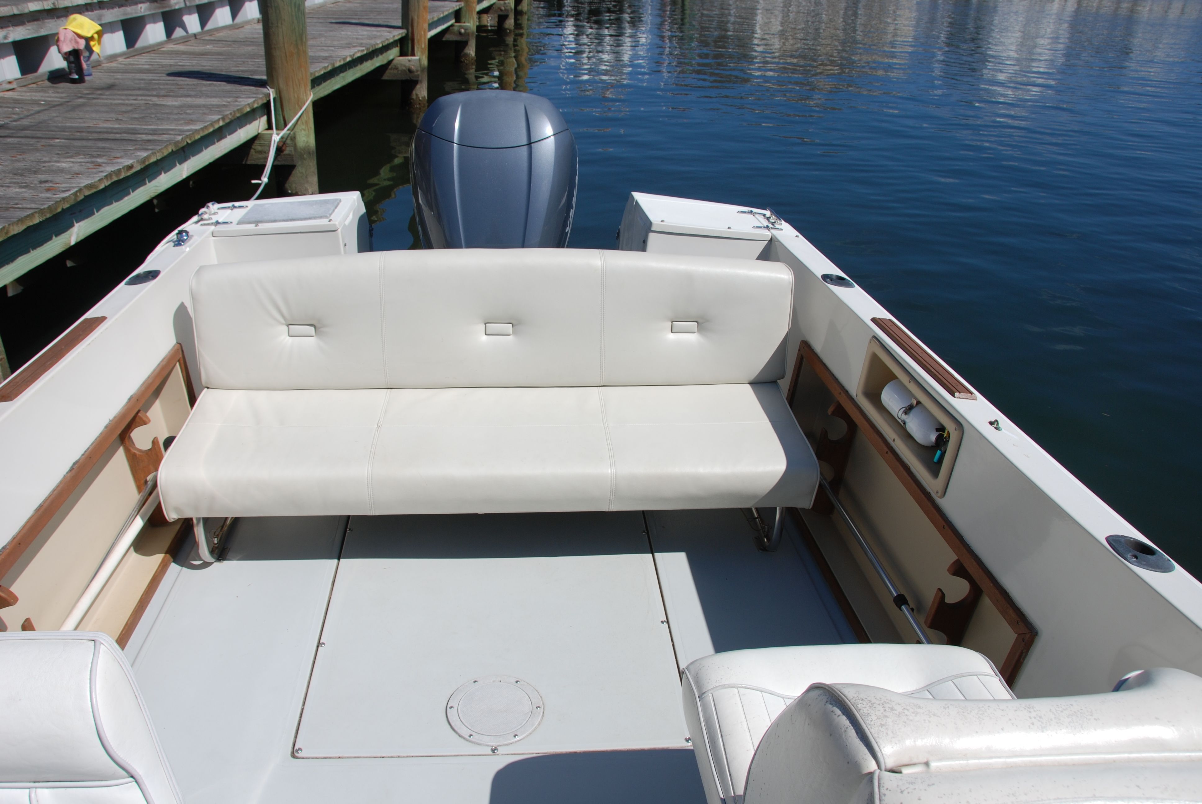 A 1987 Wellcraft V-20 Steplift with white seating, docked by the water.