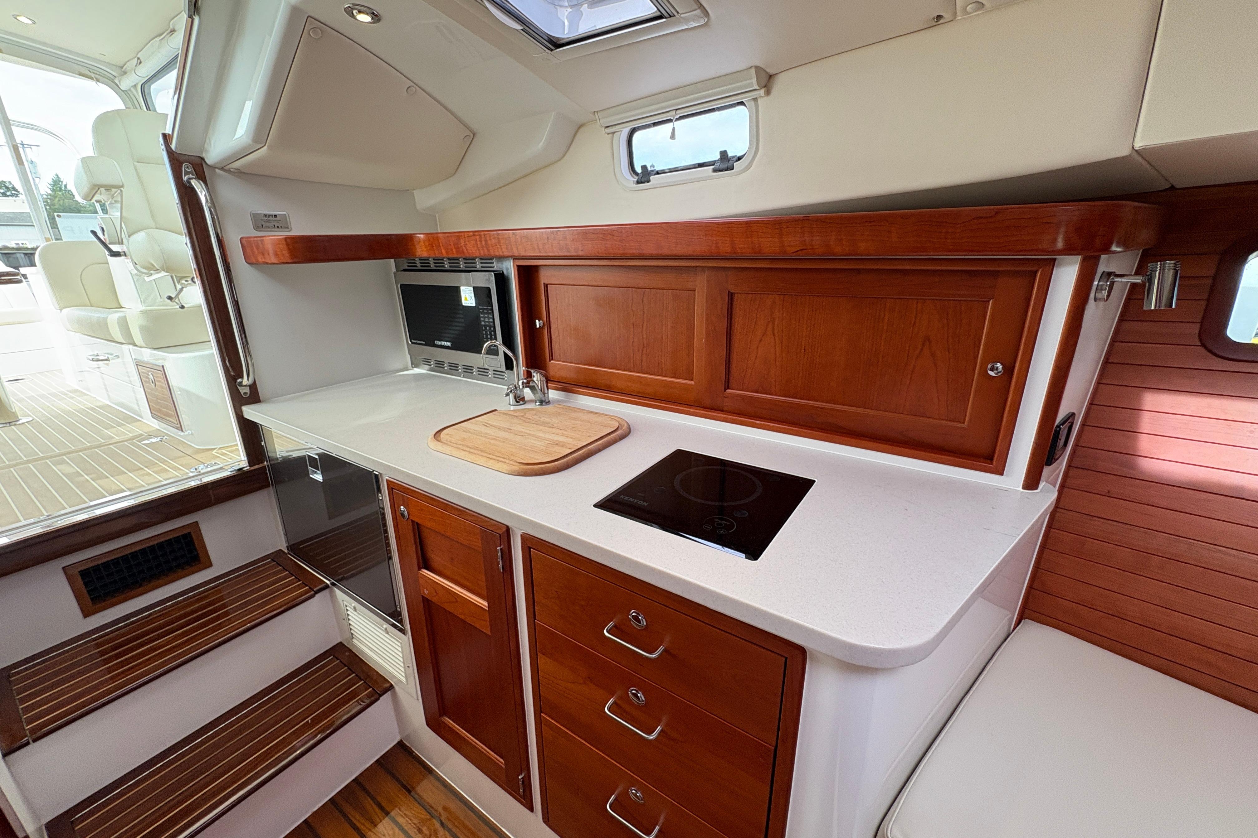 2023 MJM 35 yacht interior with modern kitchen, featuring wood cabinetry and sleek appliances.