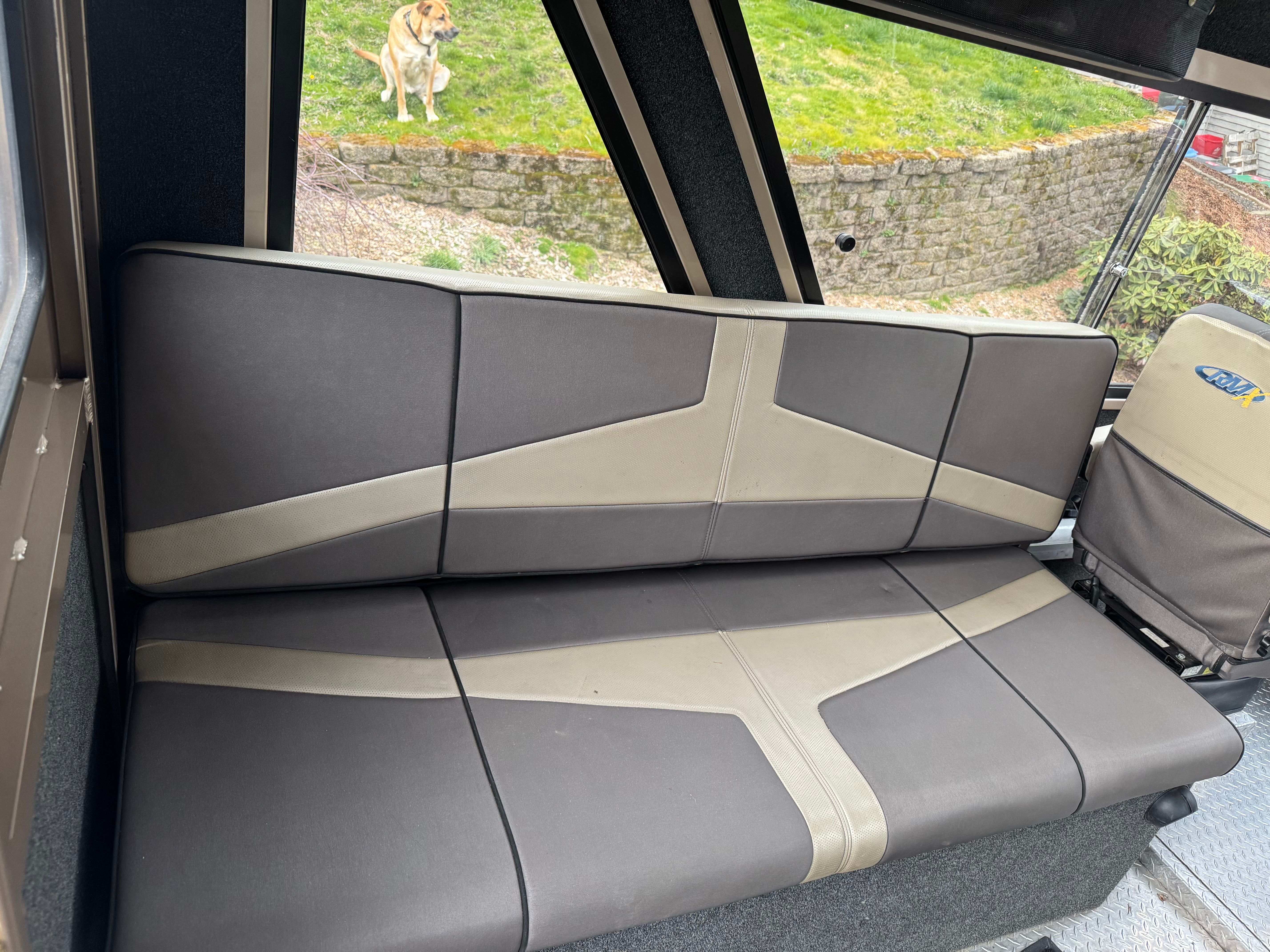 Interior of Custom RMX 24 boat, gray upholstery, dog outside.