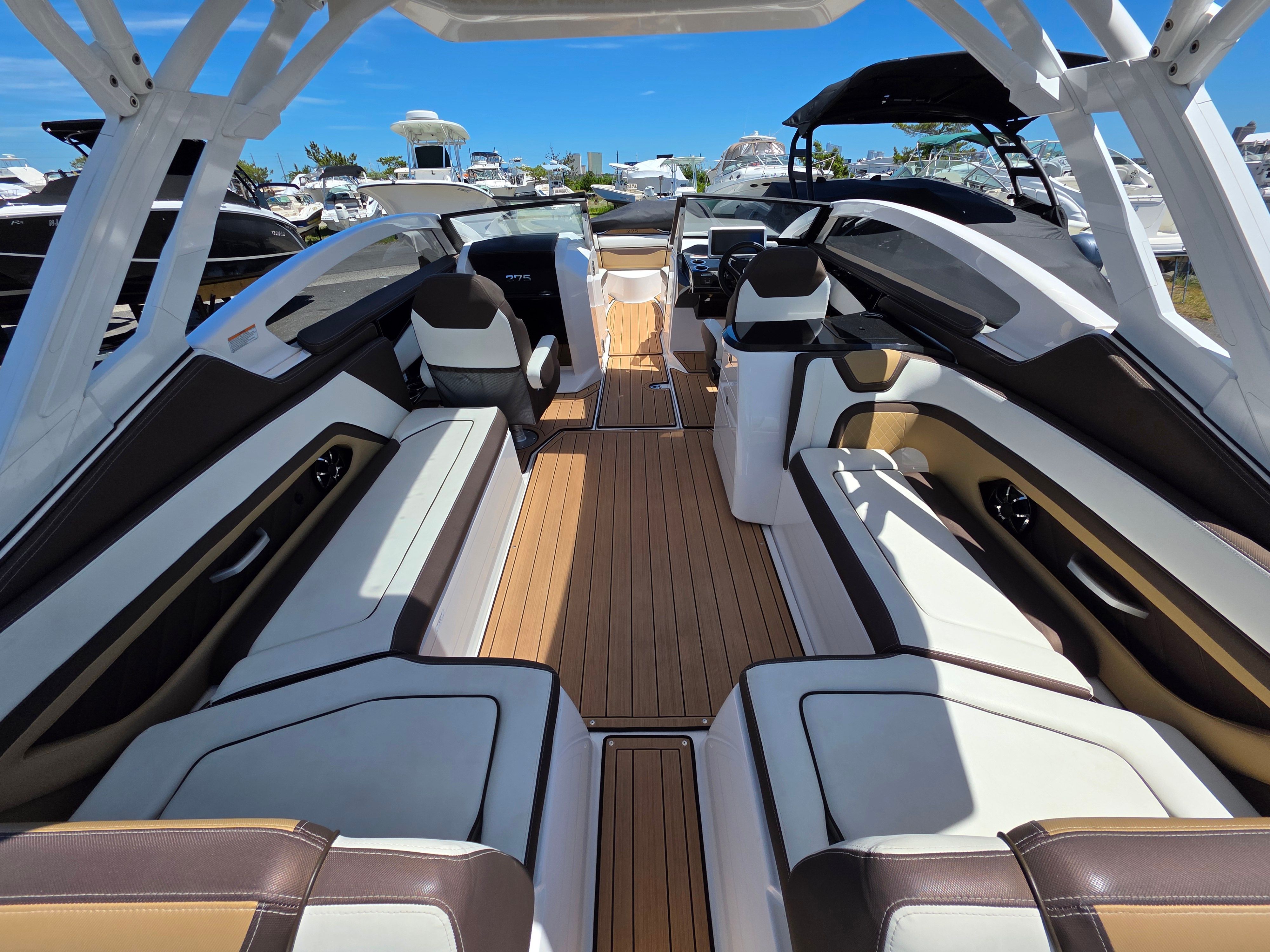 The image shows the luxurious interior of a 2023 Yamaha sd275 boat with sleek seating and wood flooring.