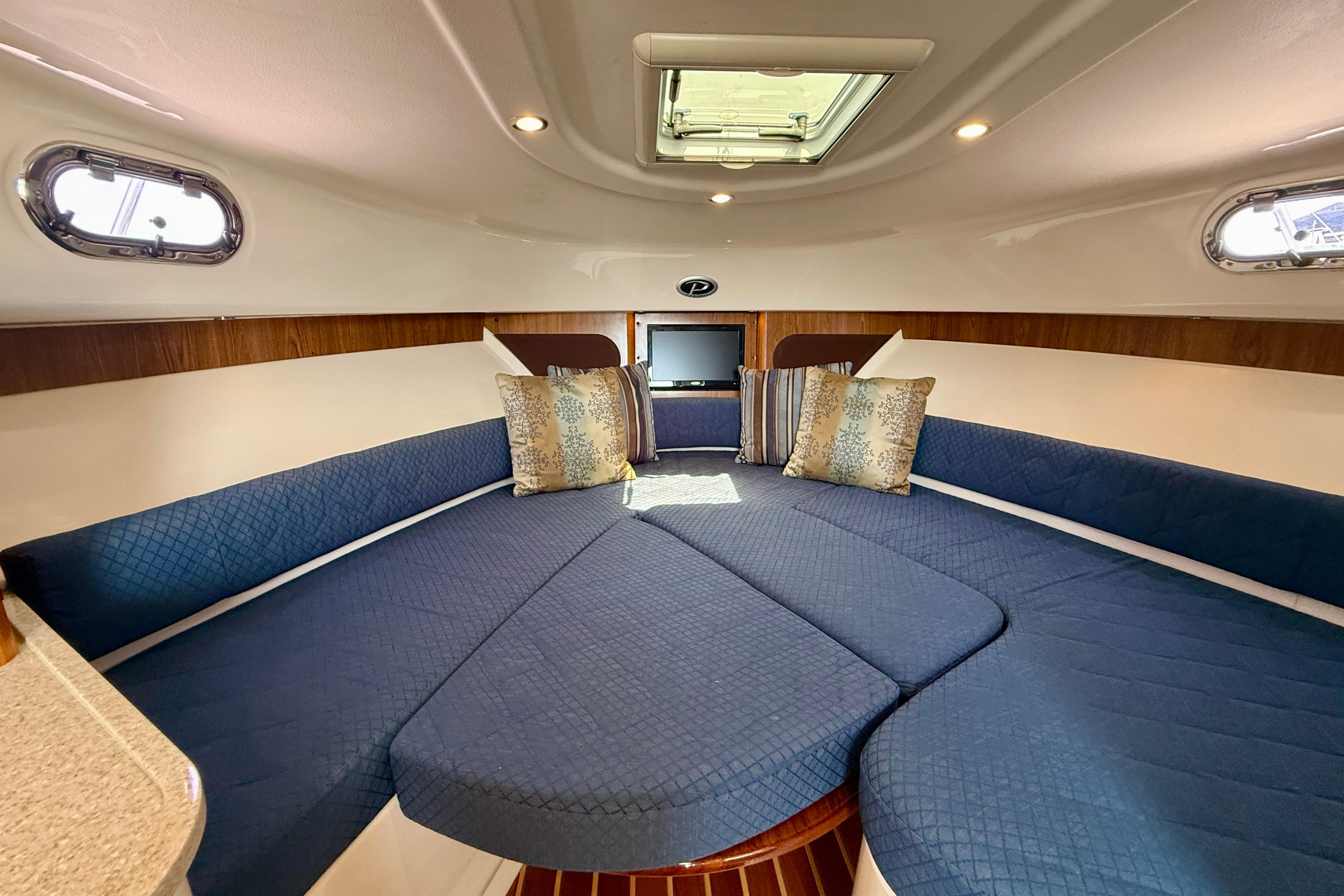 Interior of 2012 Pursuit OS 345 Offshore boat with blue seating and decorative pillows.