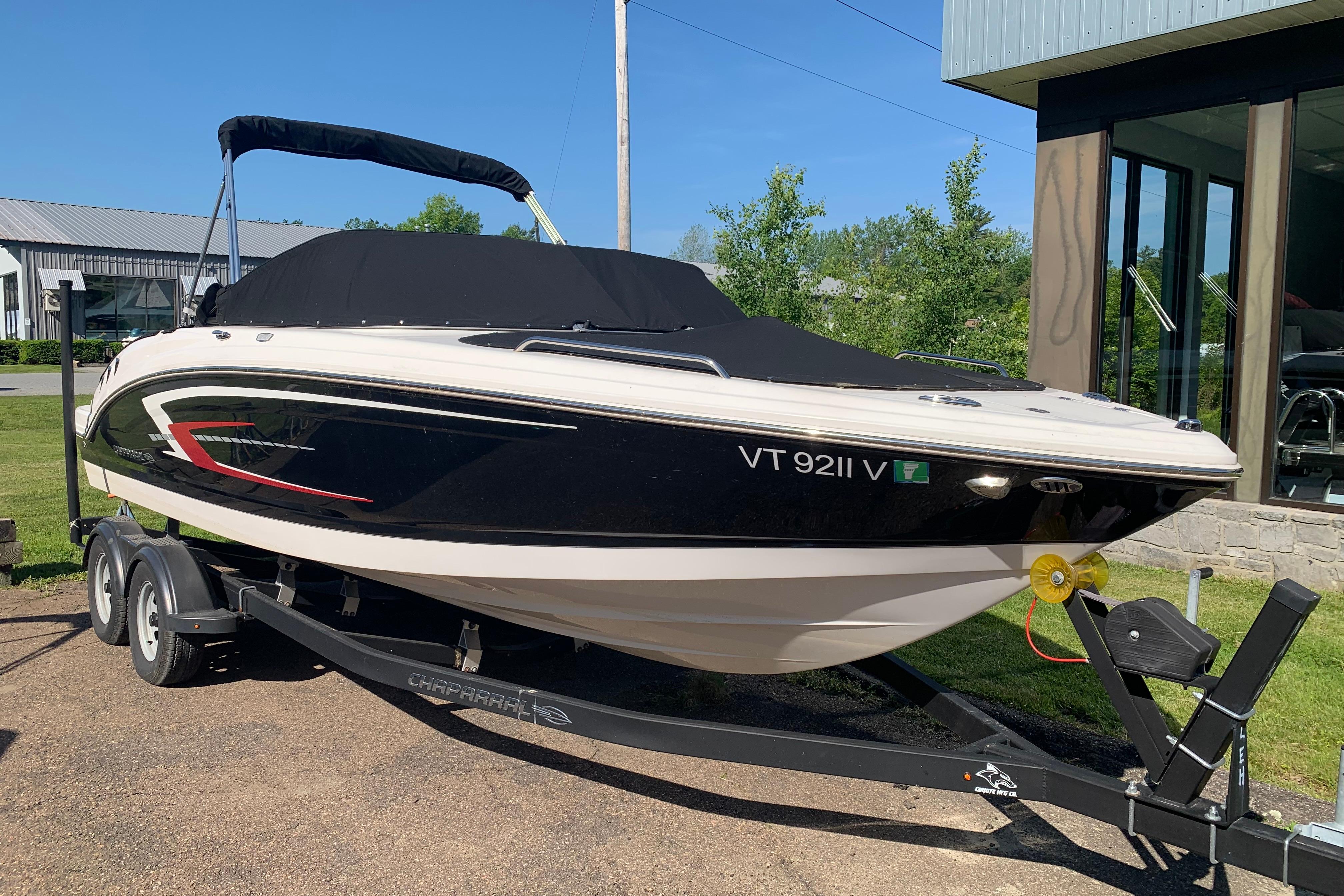 2022 Chaparral 23 SSi boat on trailer, black and white design, parked outdoors.
