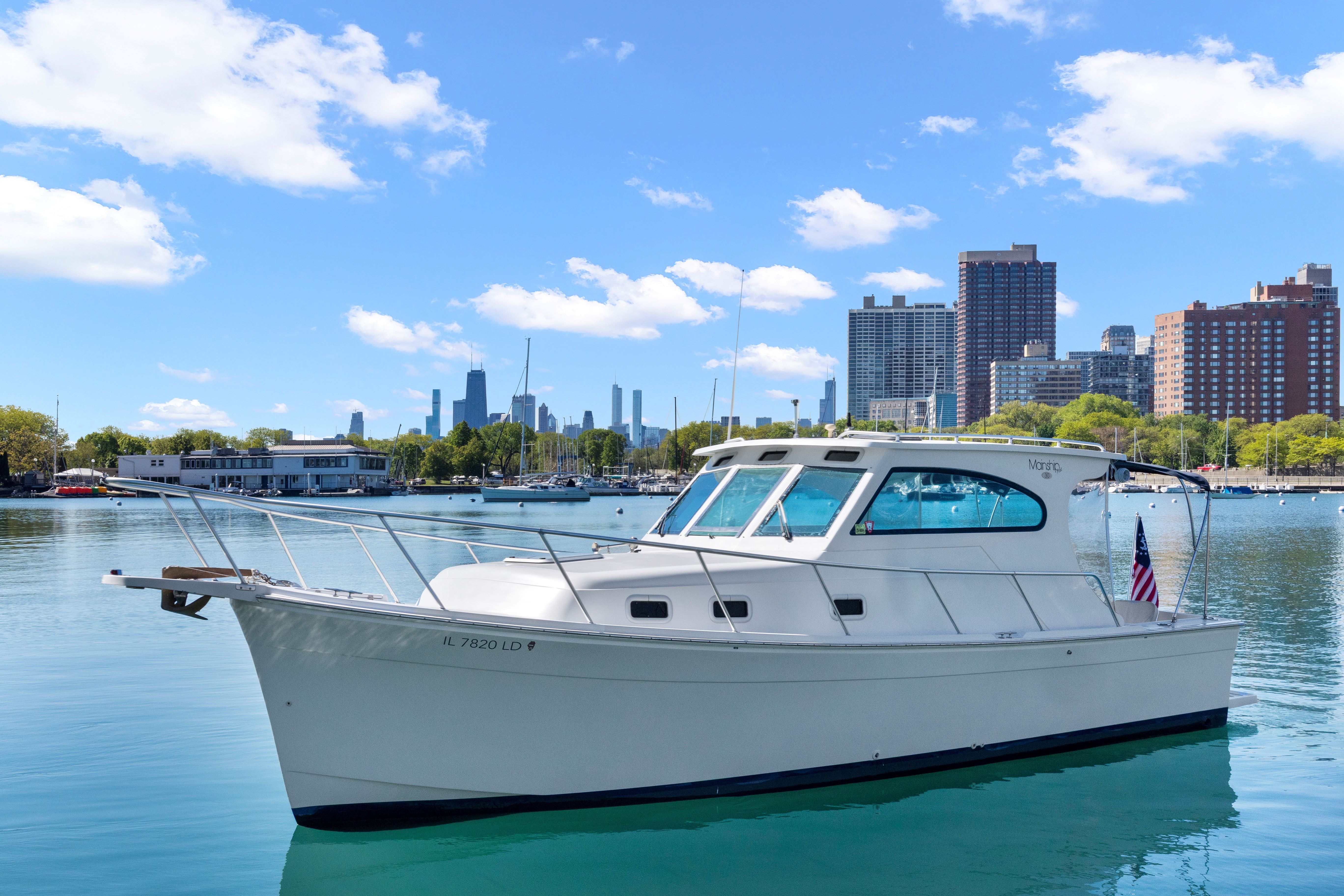 1999 Mainship Pilot 30 boat with city skyline backdrop.