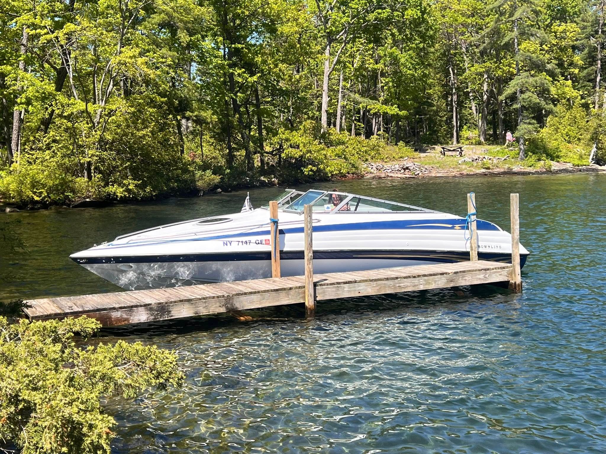 1999 Crownline 266 CCR boat docked in a wooded lakeside setting.