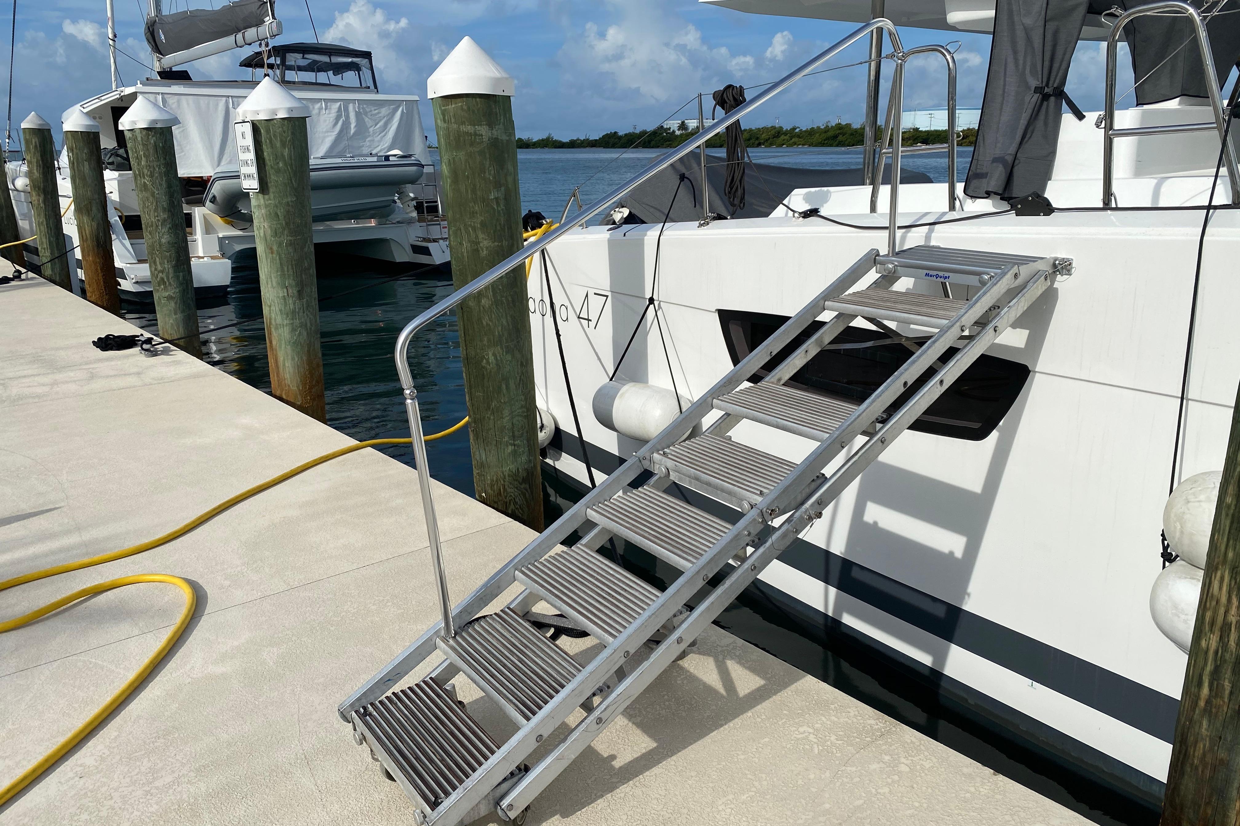 Docked 2020 Fountaine Pajot Saona 47 catamaran with boarding ladder and marina view.