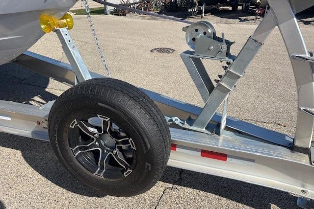 Trailer with spare tire for 2024 Chaparral 30 Surf boat, parked on pavement.