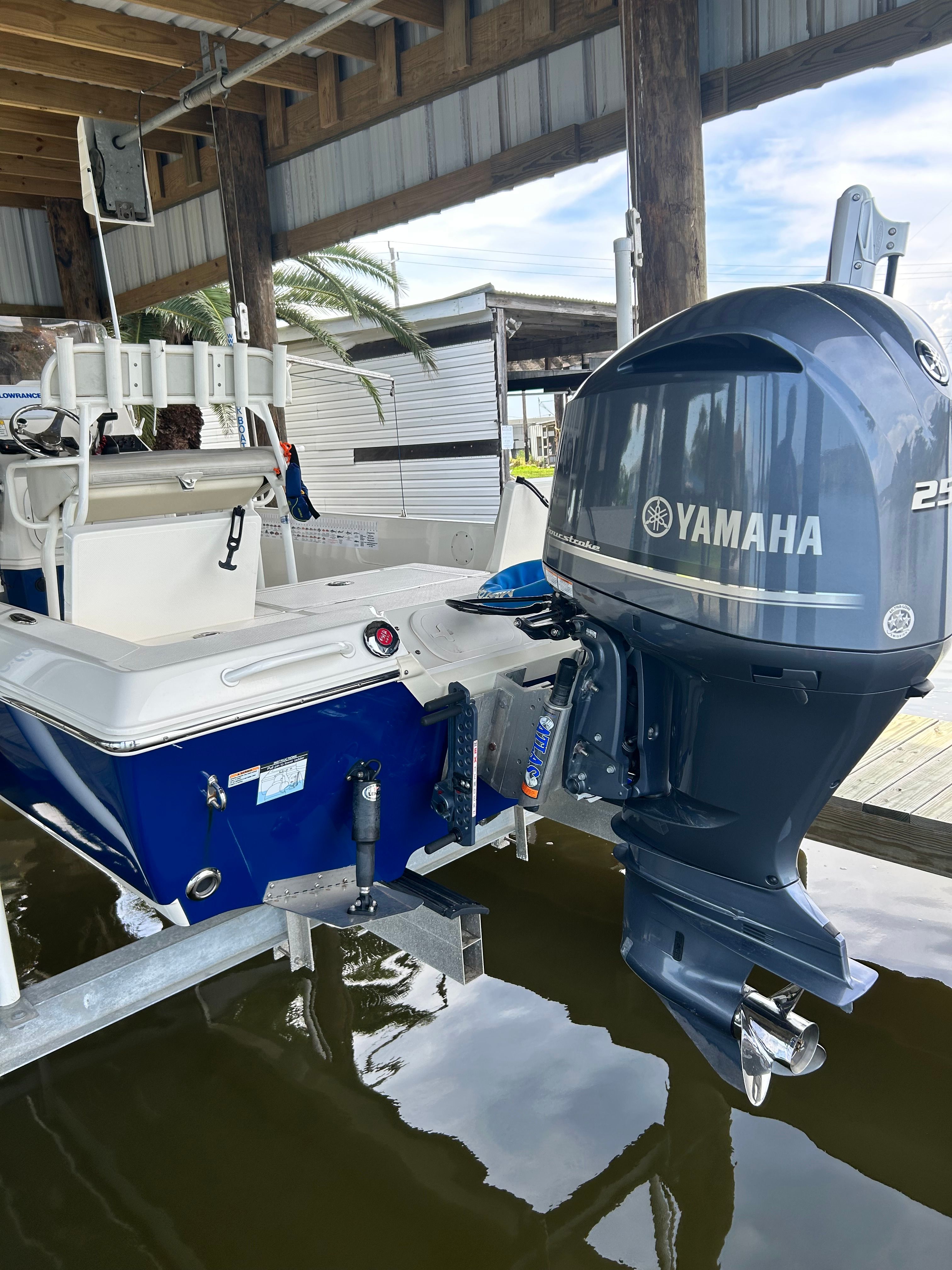 A blue 2016 Skeeter SX230 boat with a Yamaha outboard motor, situated in a covered dock.