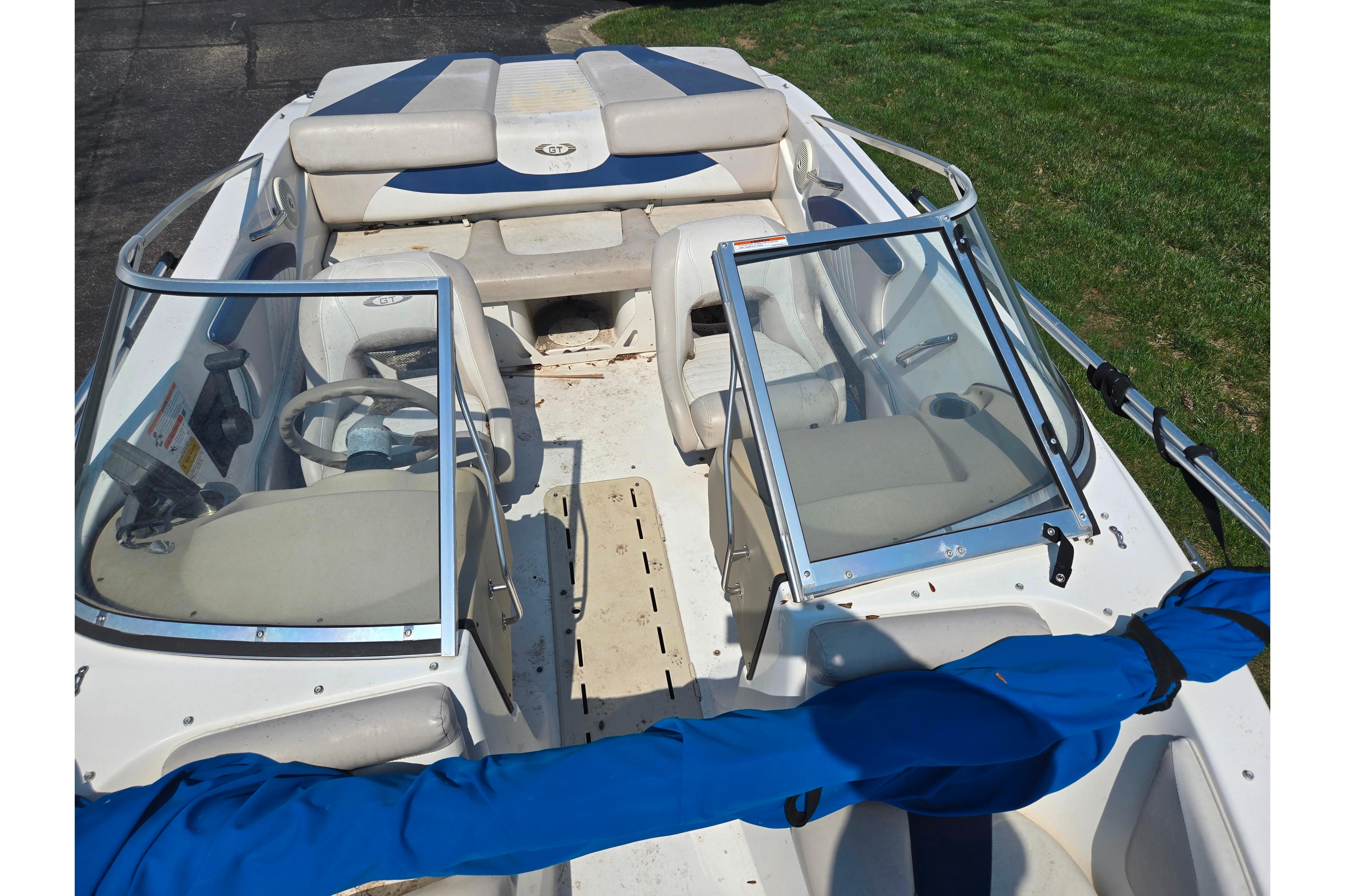 2007 Glastron GT 185 boat interior with seating and steering wheel, parked on grass.