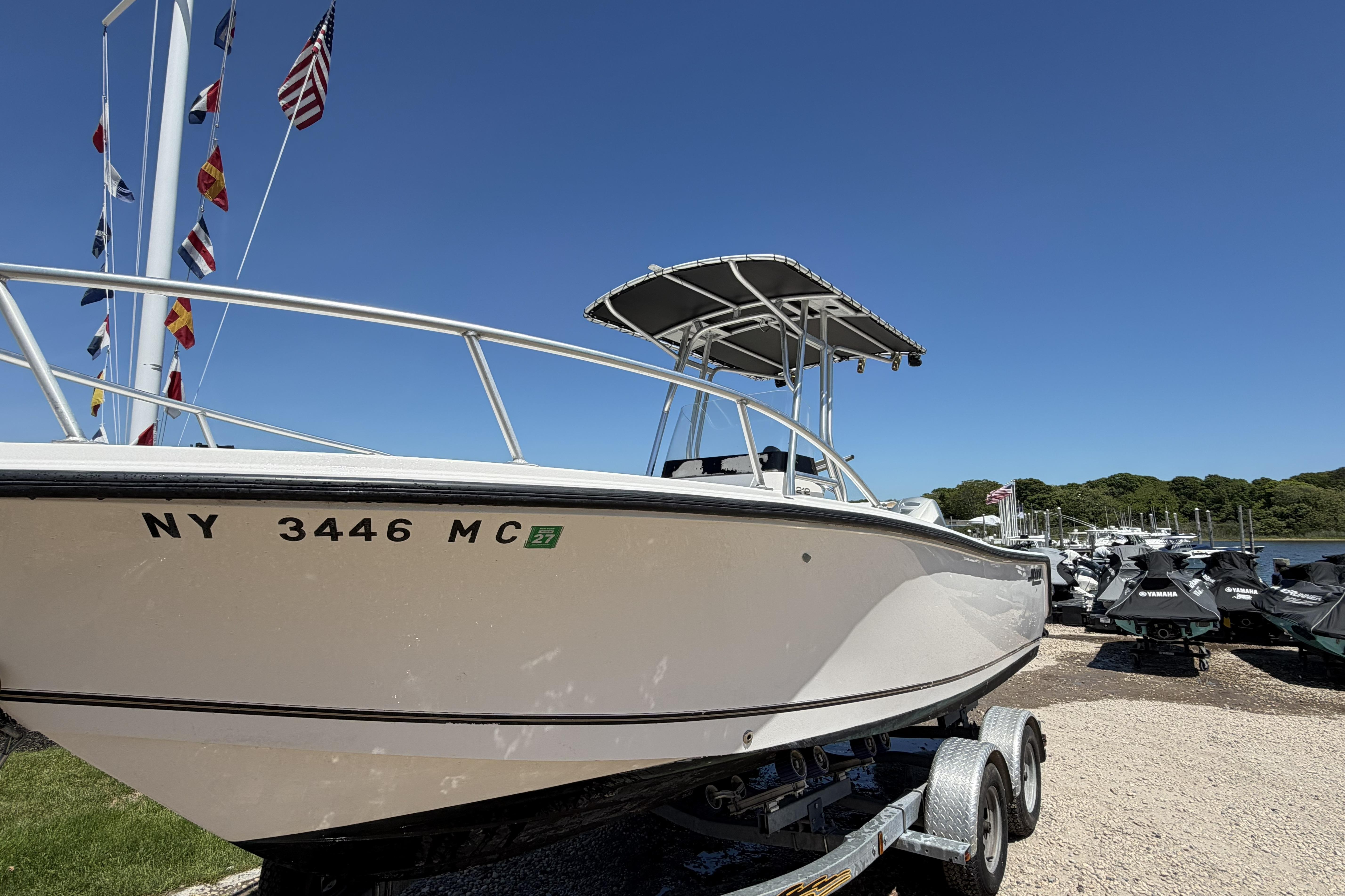 2006 Mako 212 Center Console boat on trailer, with flags and clear blue sky.