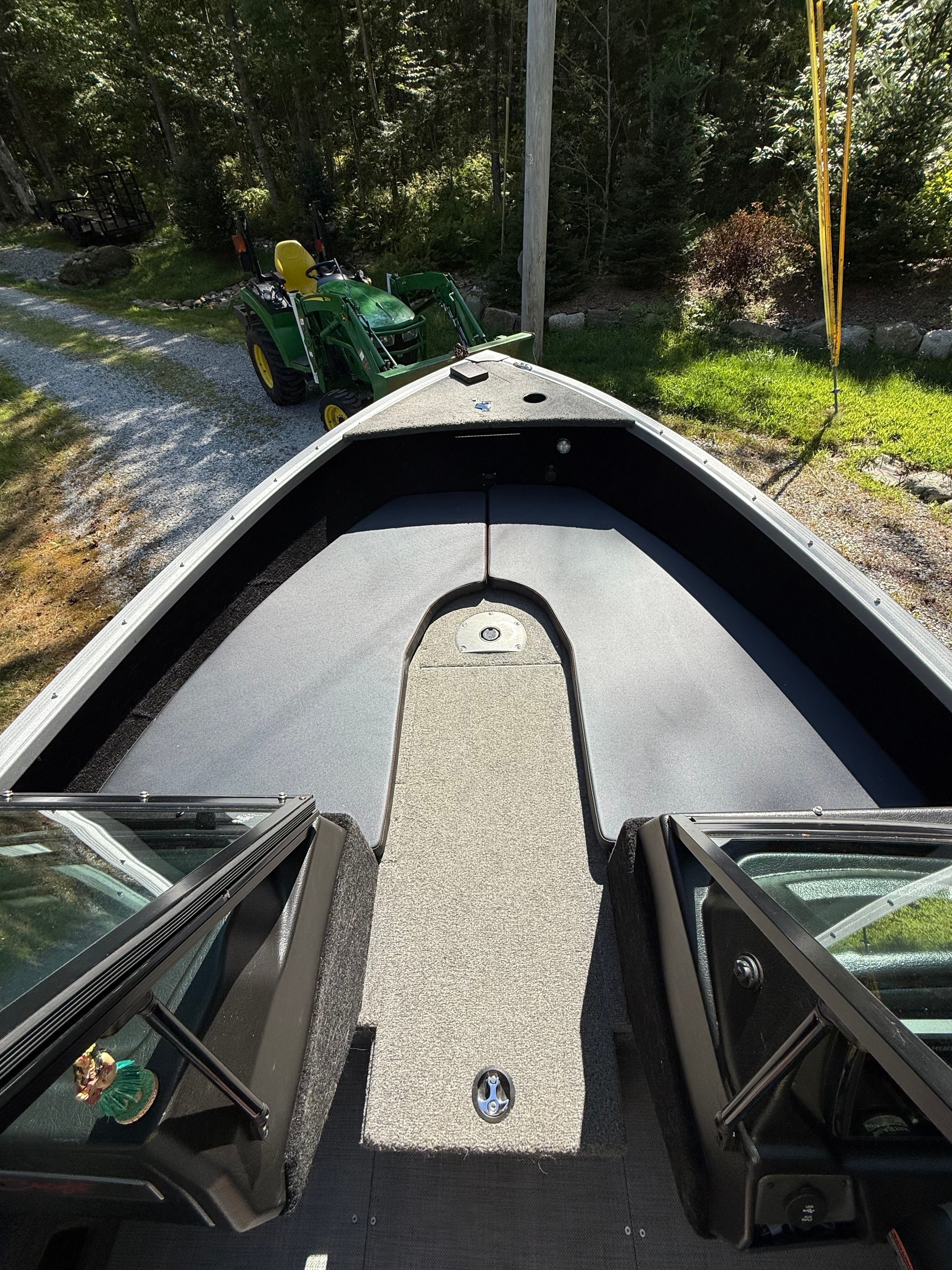 Alumacraft Competitor 175 Sport 2022: Bow deck with gray carpet, surrounded by trees.